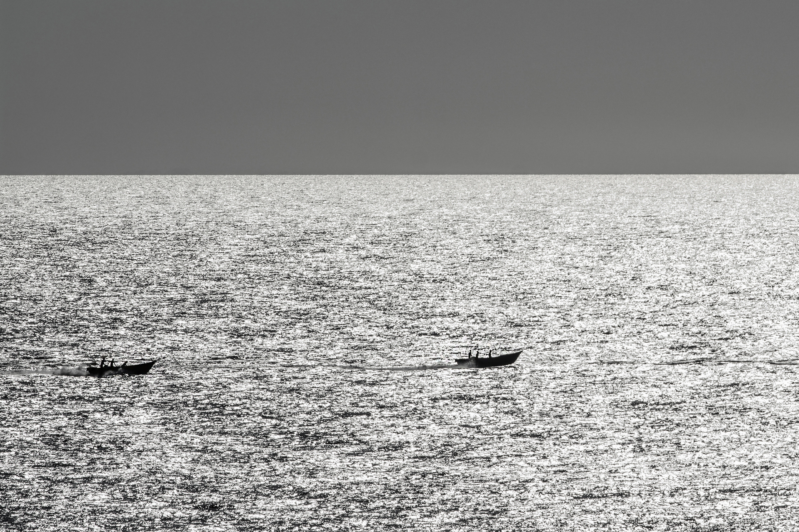 Рыболовные суда на золотистой поверхности океана, чб