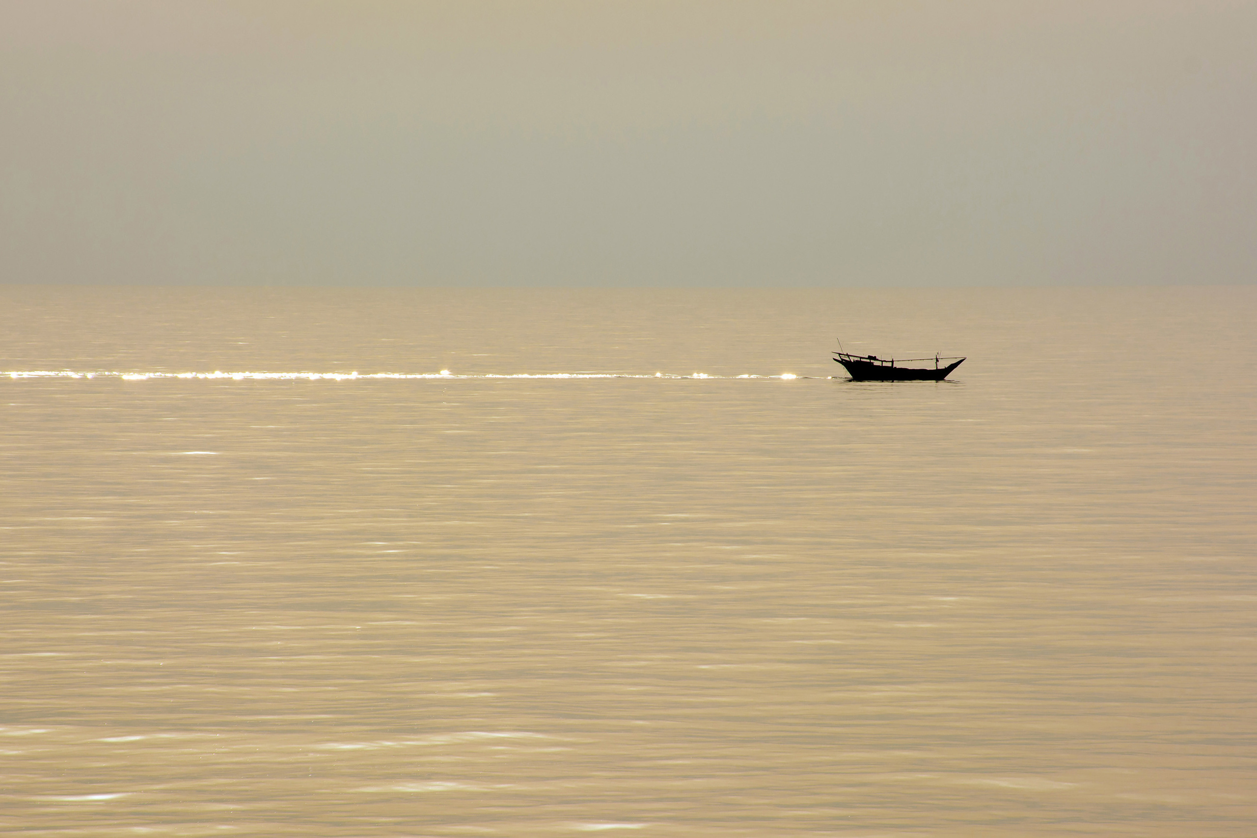 Рыболовное судно на золотистой поверхности океана