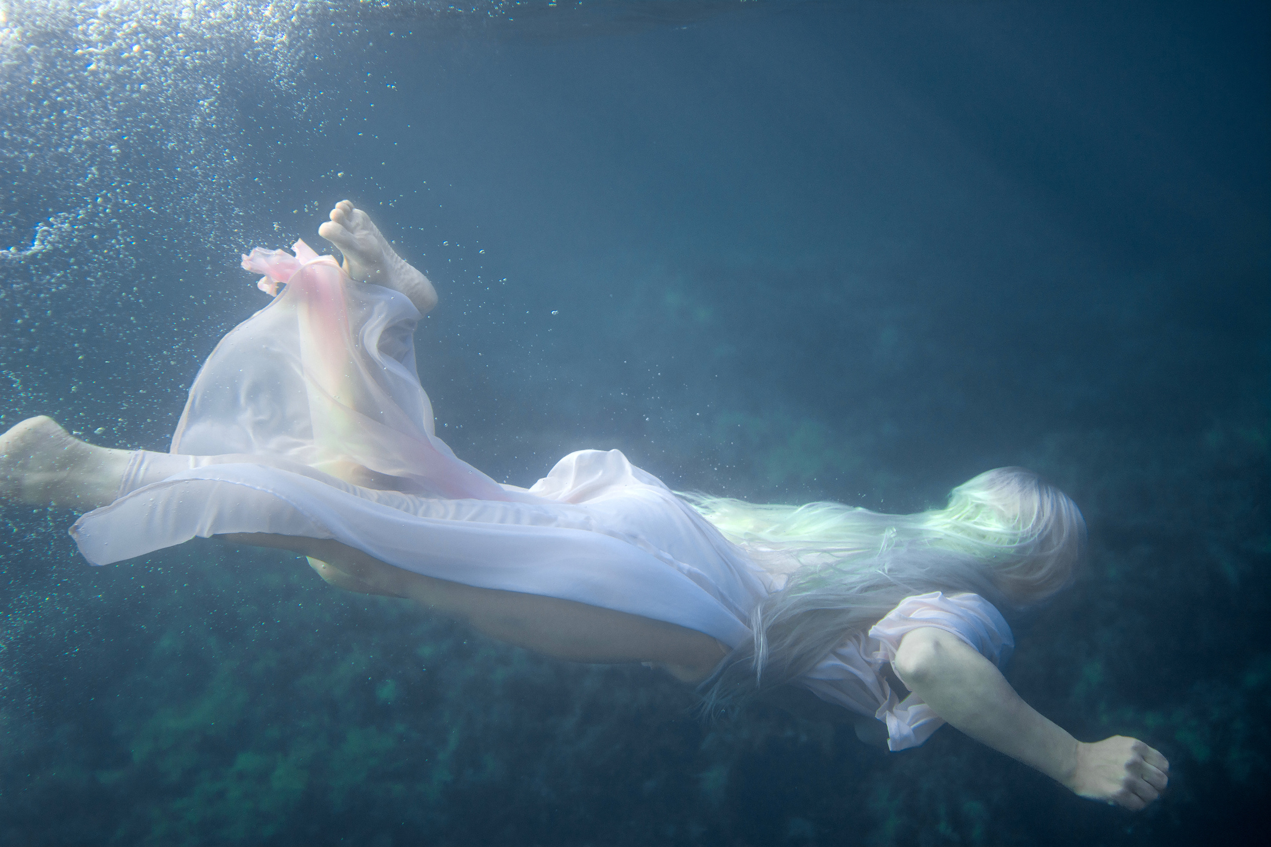 Девушка в розовом плывет под водой