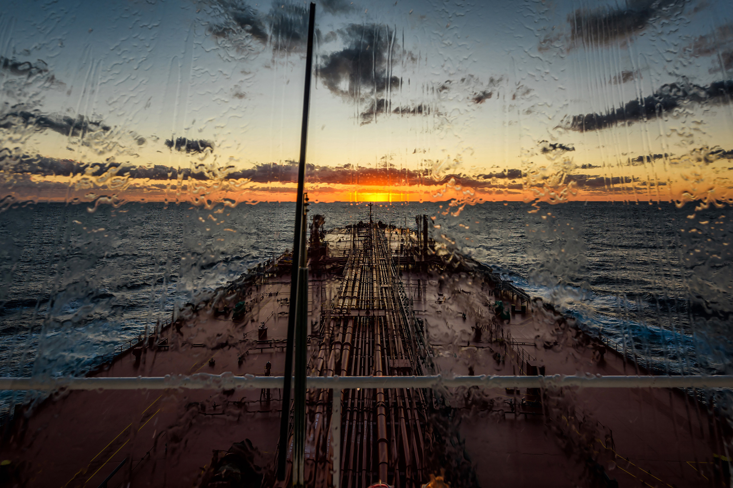 Палуба танкера сквозь иллюминатор мостика в дождь