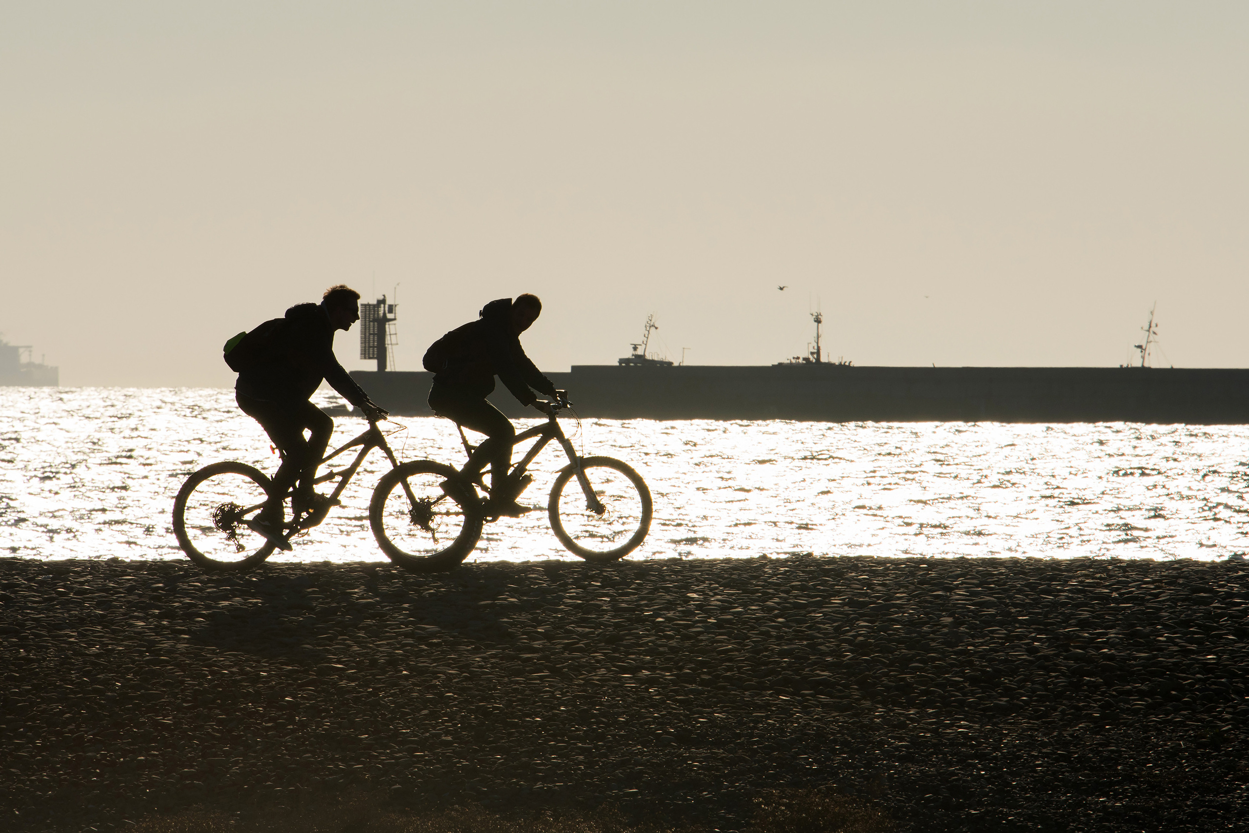 Силуэты двух велосипедистов едущих по морскому пляжу, Новороссийск