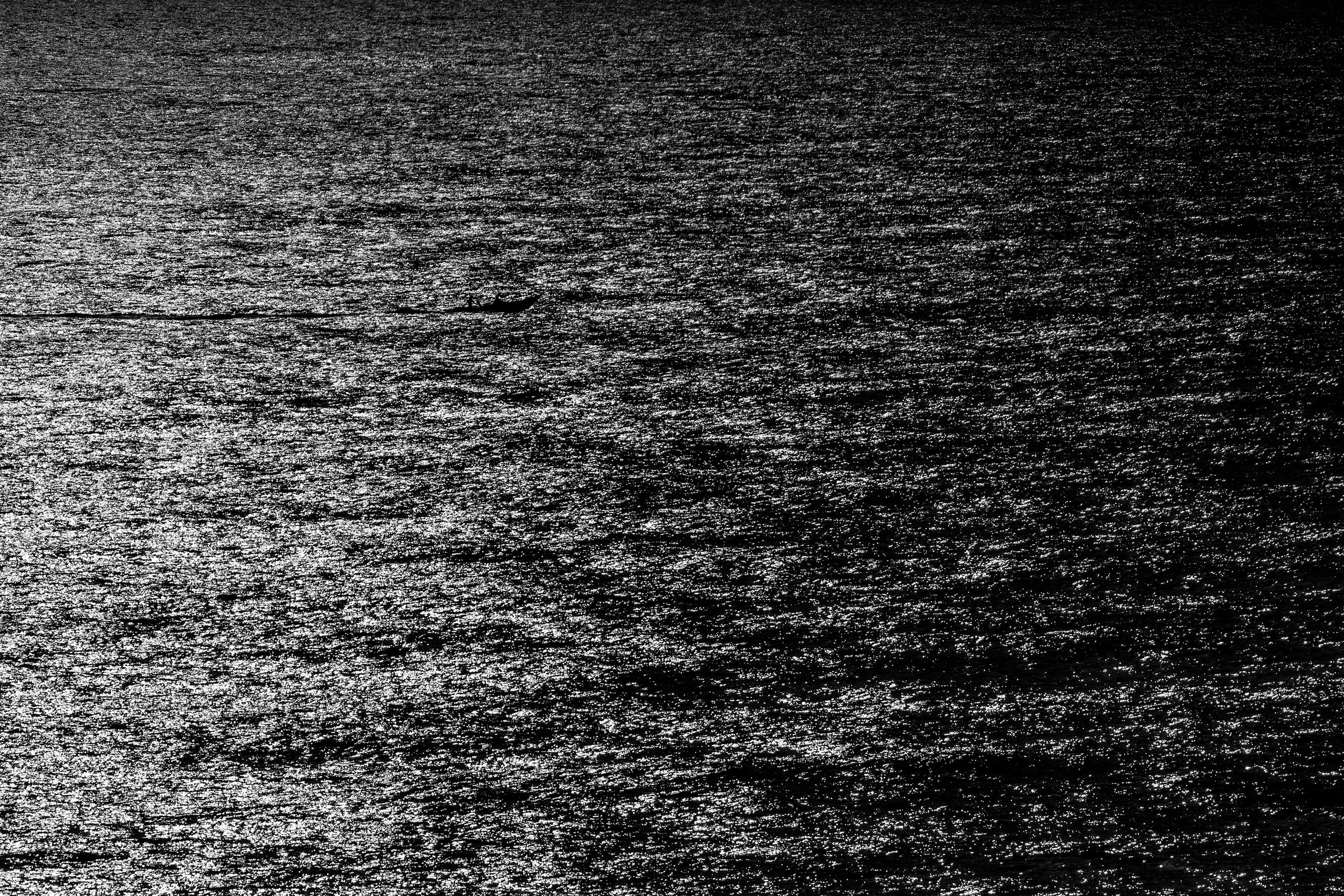 Водная поверхность с лунными бликами и рыбацким судном, чб