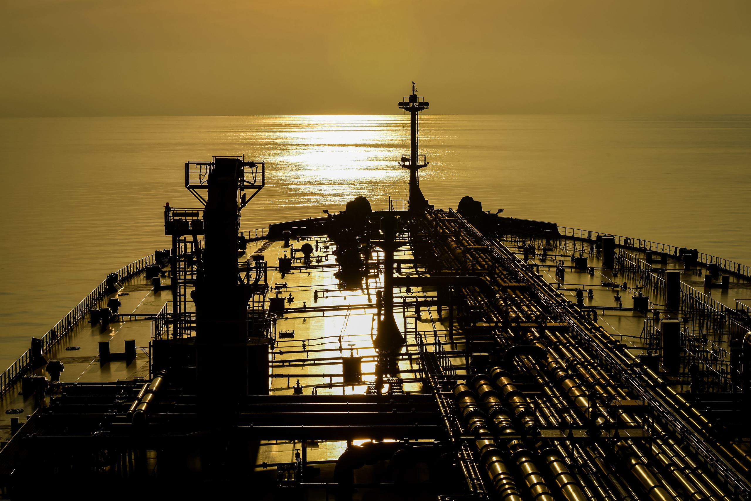 Нос, палуба танкера, двигающегося на заходящее Солнце