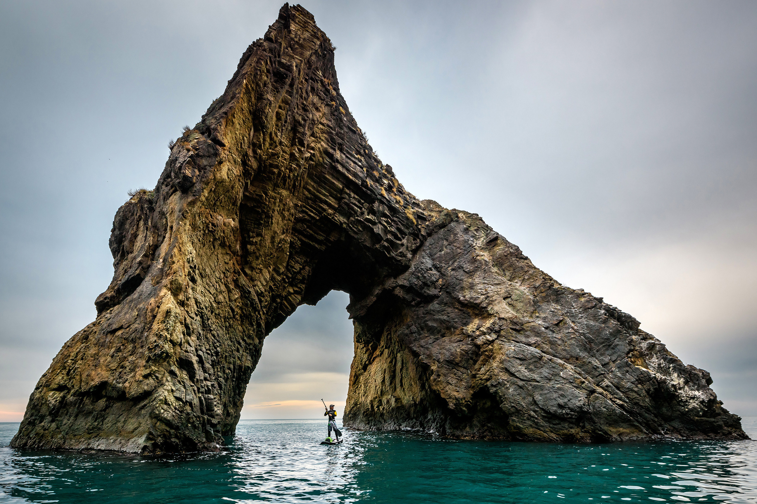 Скала с аркой и парень на САП-борде