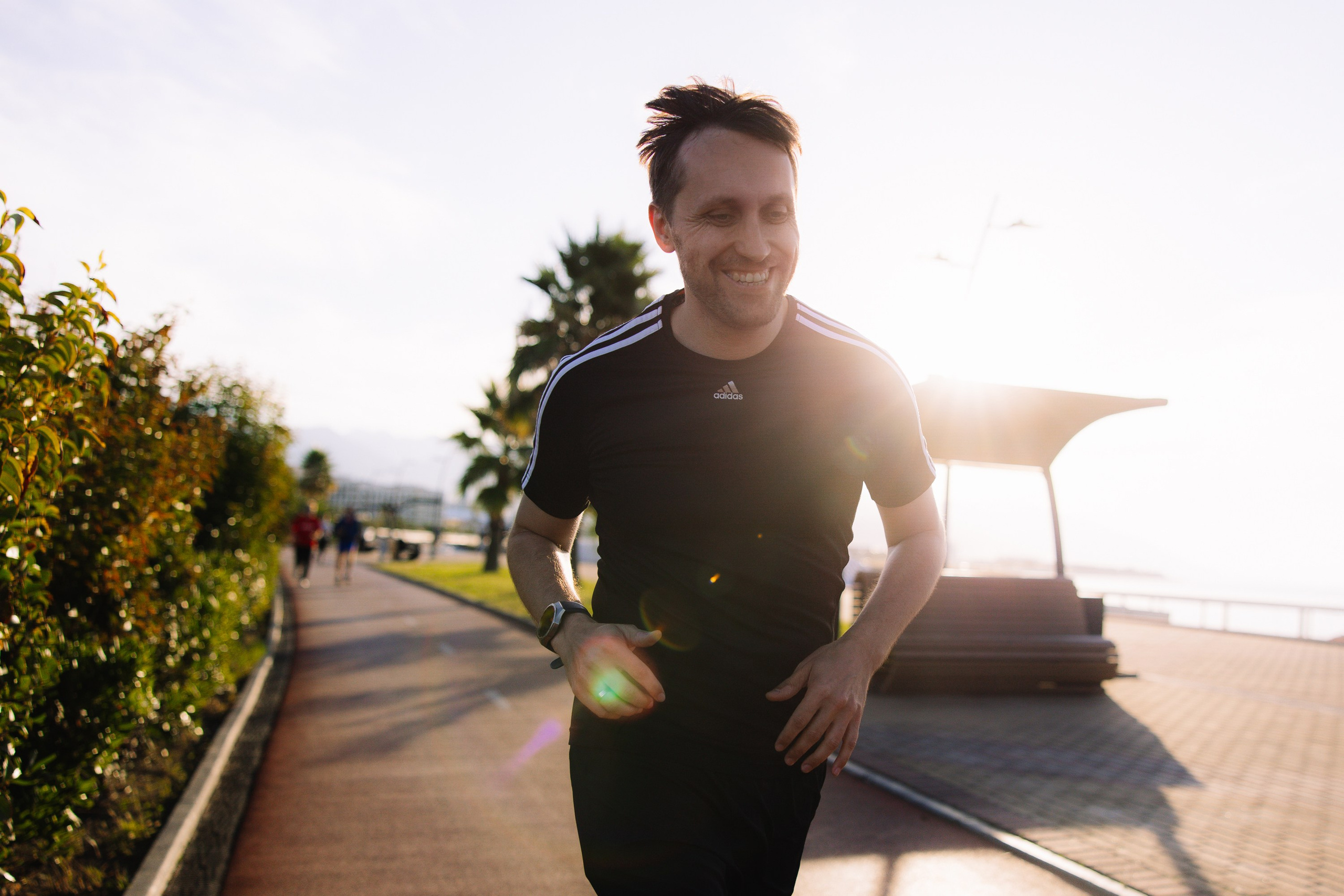 Портрет: Мужчина в спортивной одежде на фоне морского побережья в лучах утреннего солнца.