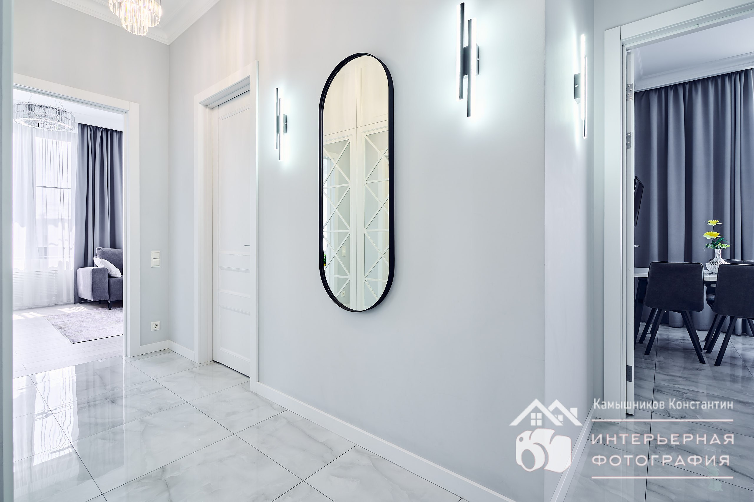 Интерьерная фотография коридора в квартире бизнес-класса с открытыми дверьми в гостиную и на кухню, искусственный доступный свет