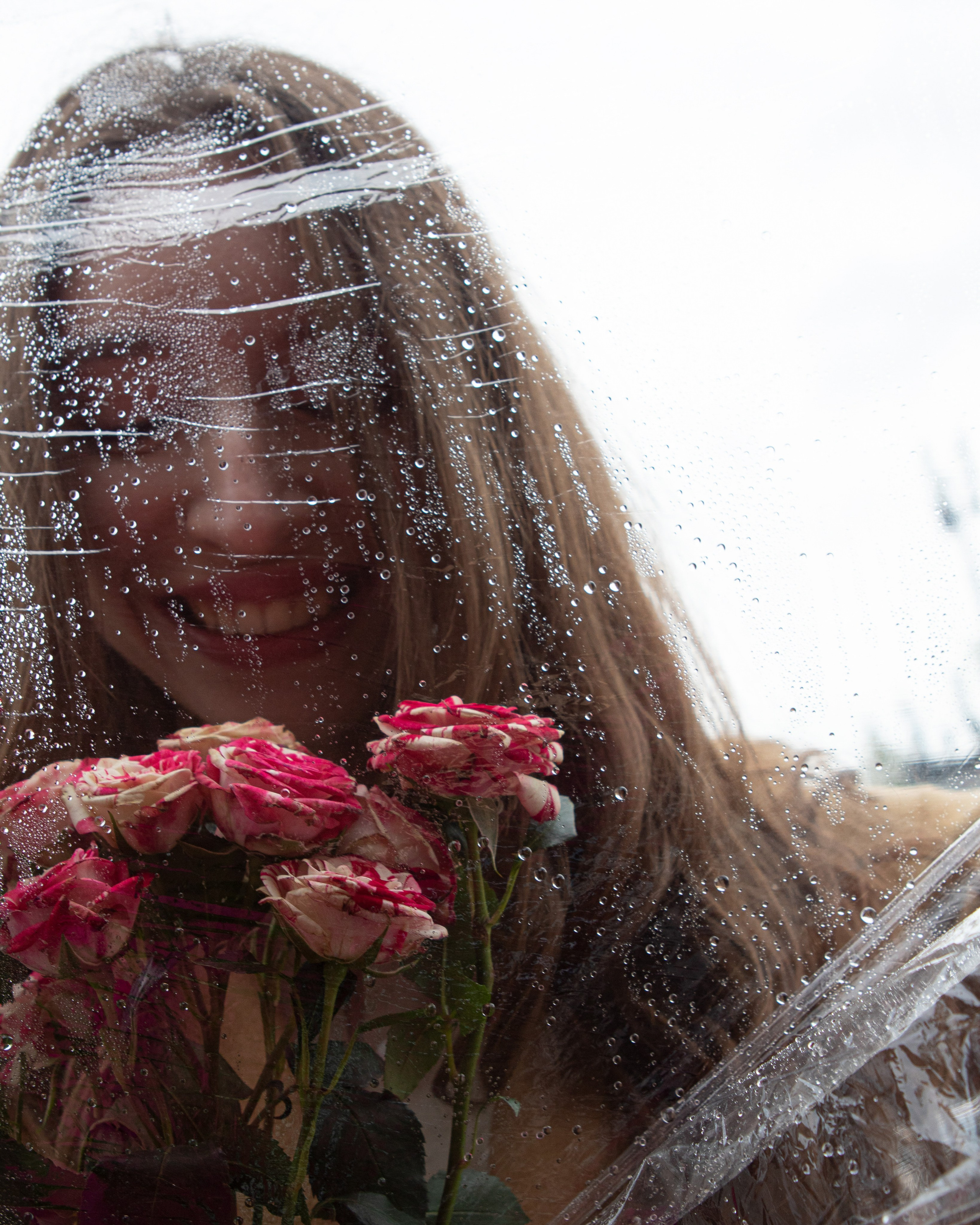 изображение молодой девушки через капли дождя 