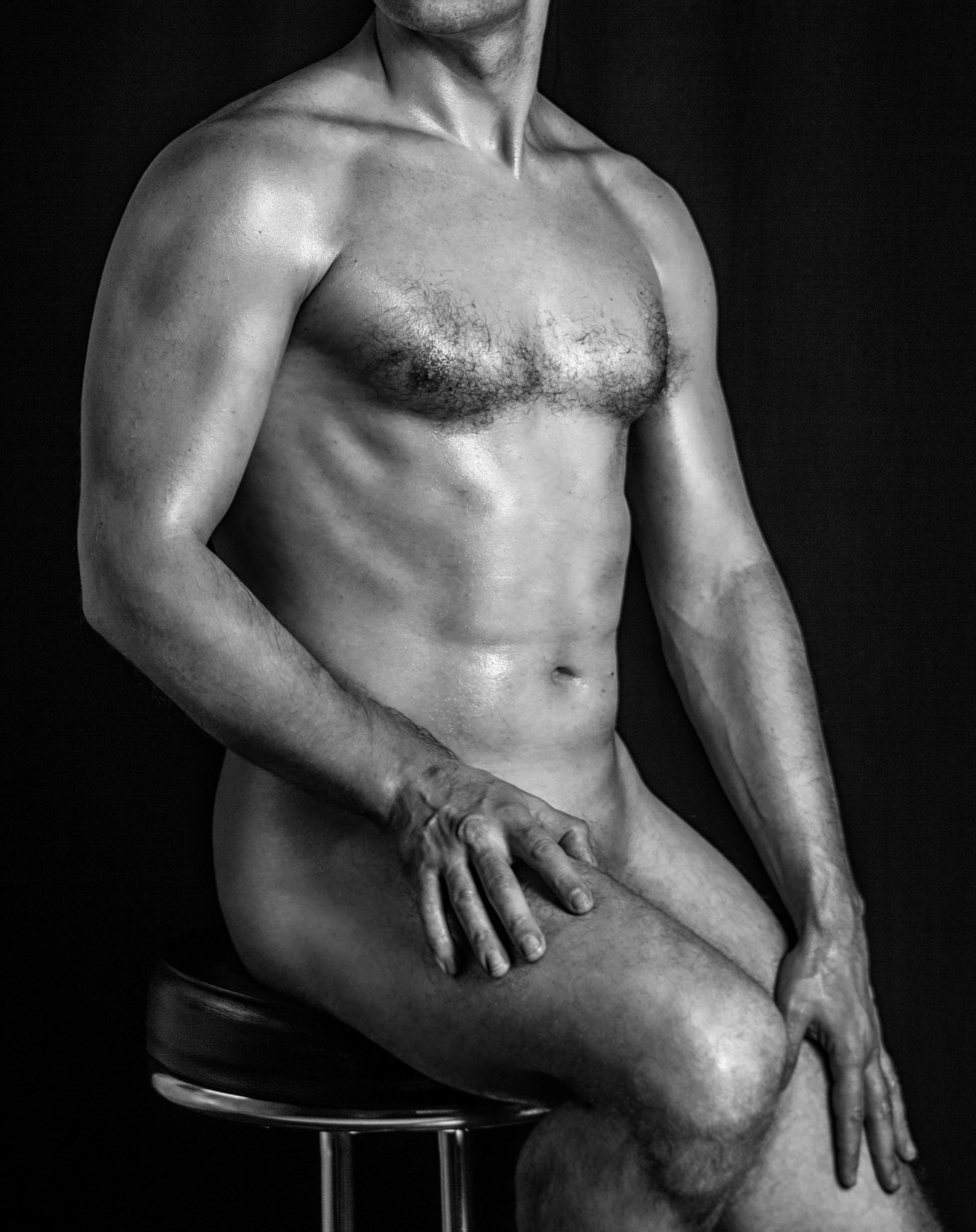 обнаженный  мужчина  сидит на  барном  стуле. фотография  черно  белая.
