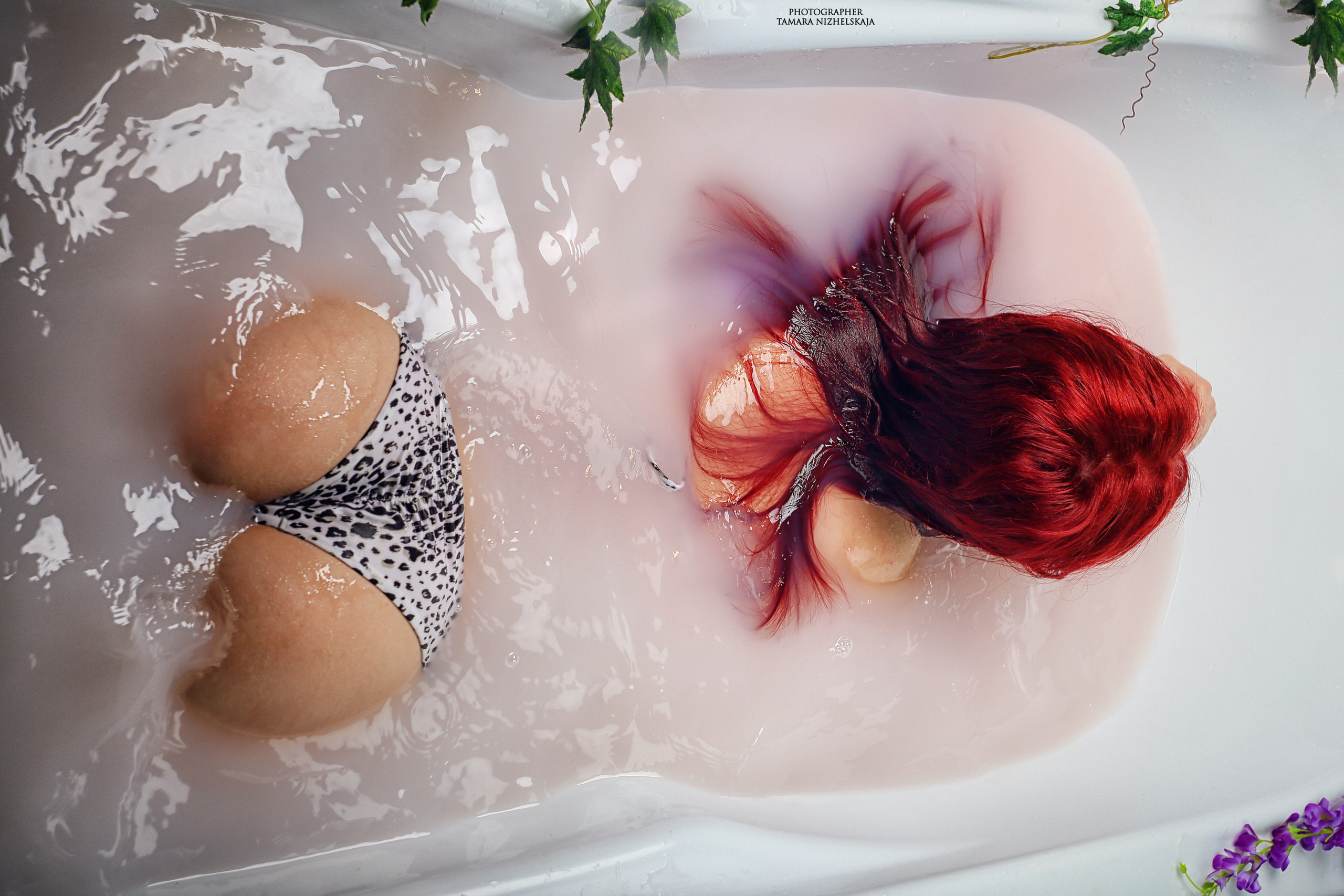 девушка  с  красными волосами в леопардовом  купальнике лежит   в ванной. попка еле  видна  из воды.