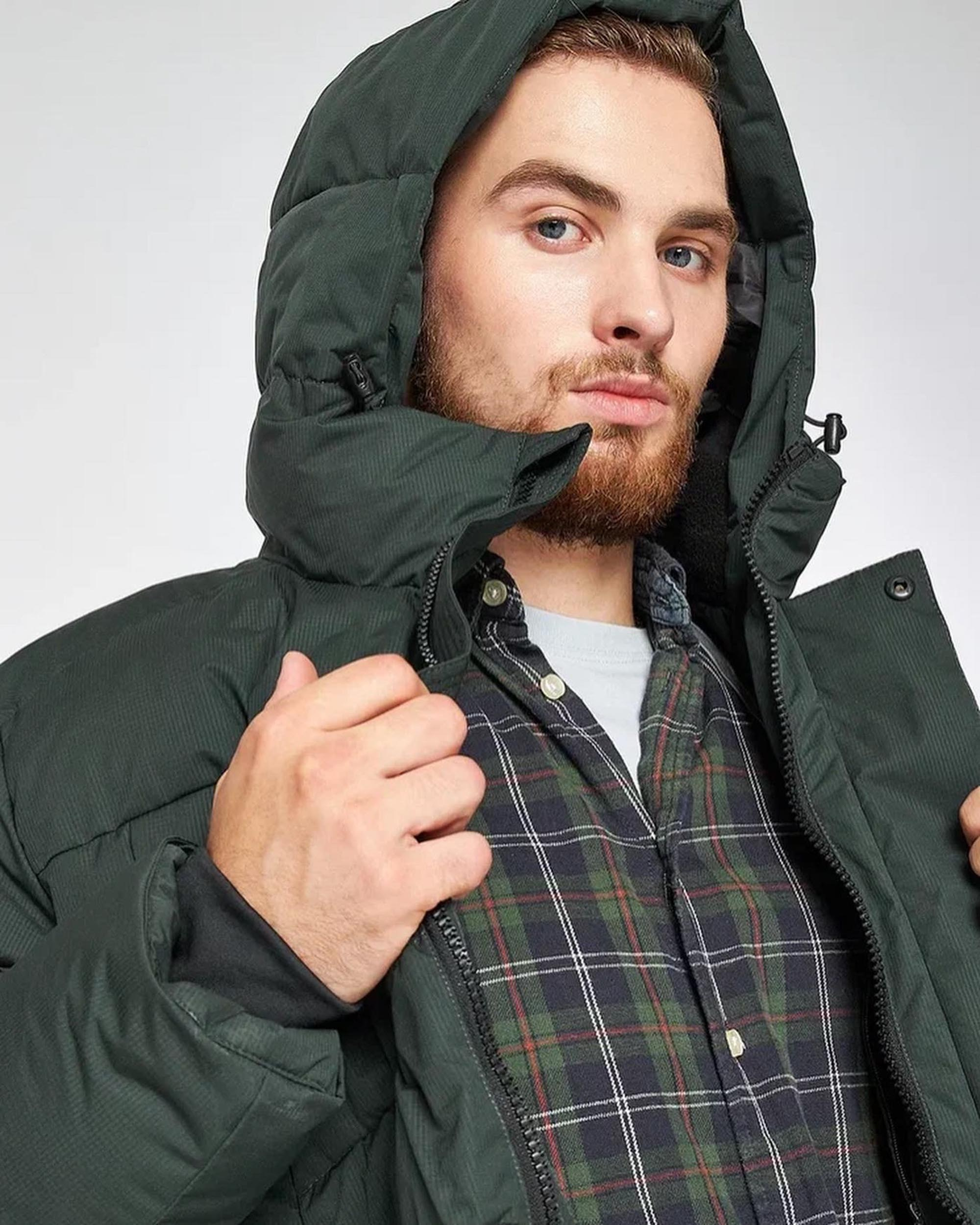 Мужчина с бородой в зеленой теплой куртке с капюшоном