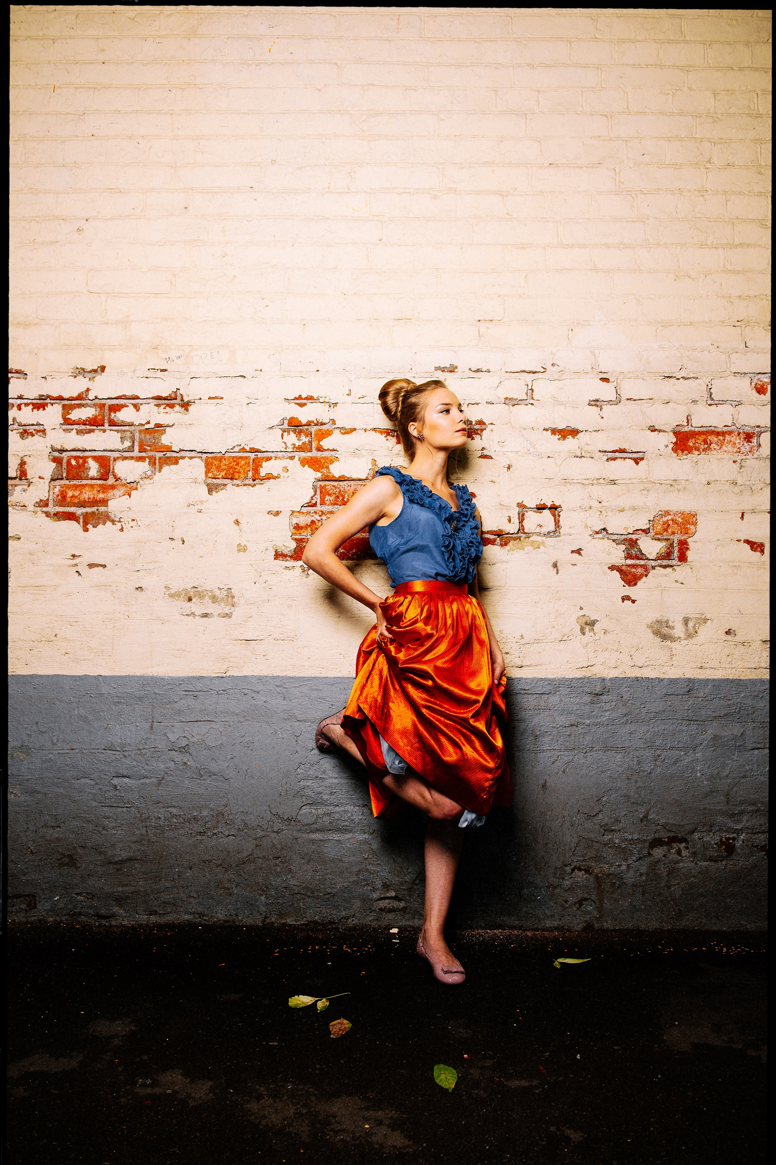 Ольга Арнтгольц в яркой оранжевой юбке на фоне стены