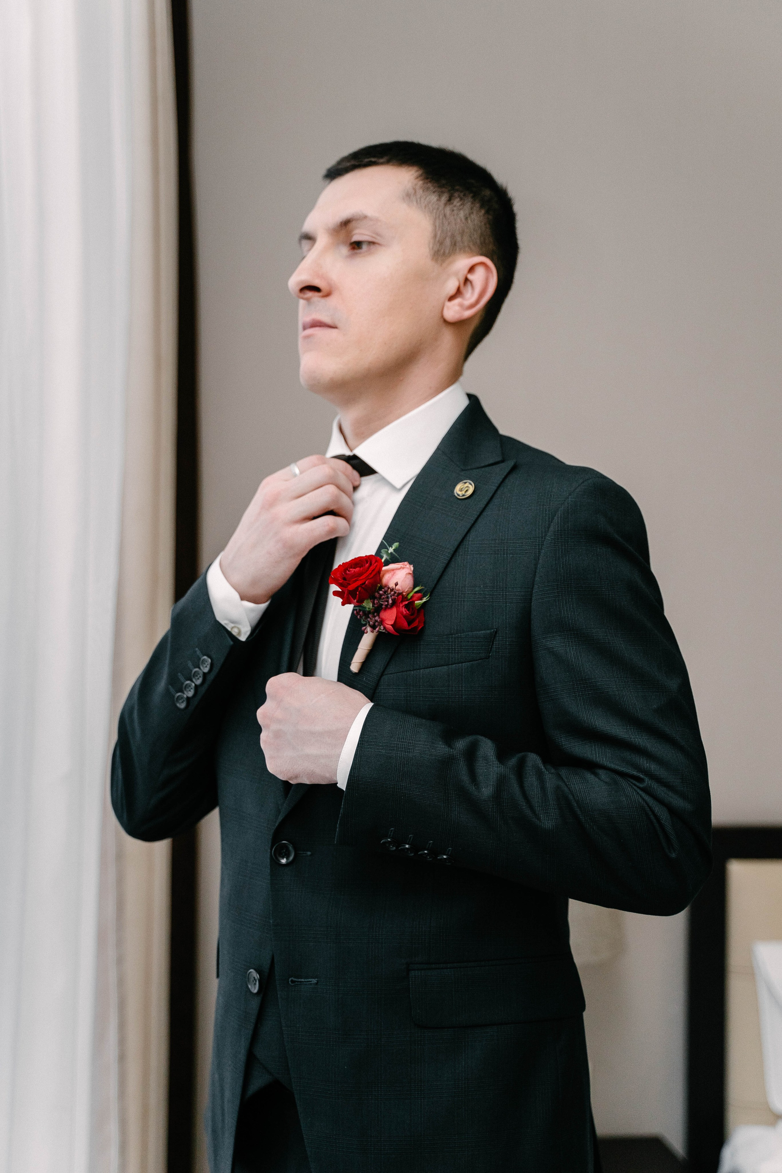 сборы жениха в отеле с красной бутоньеркой