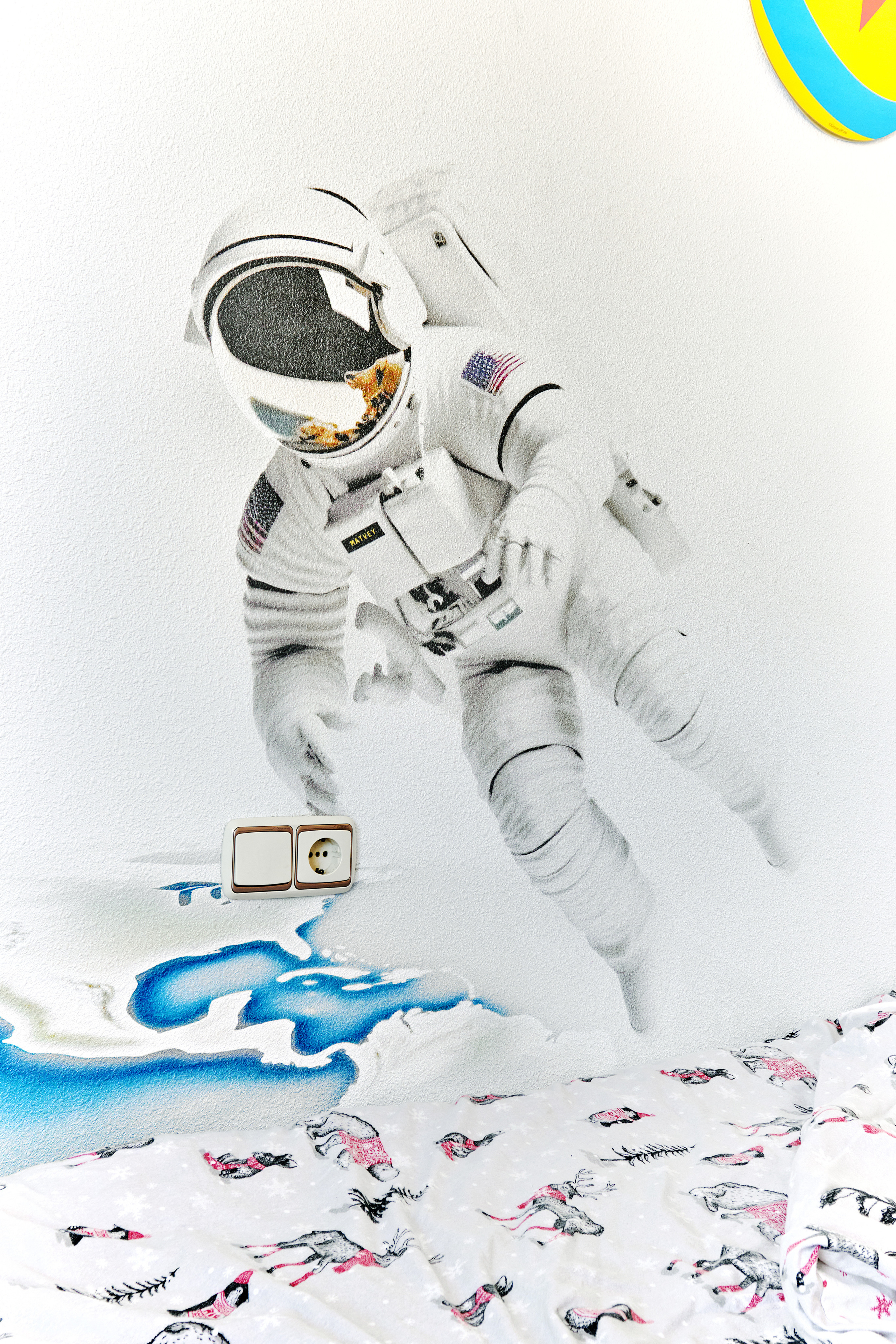 Mural artístico y graffiti sobre un tema espacial en la pared de una habitación infantil en España.