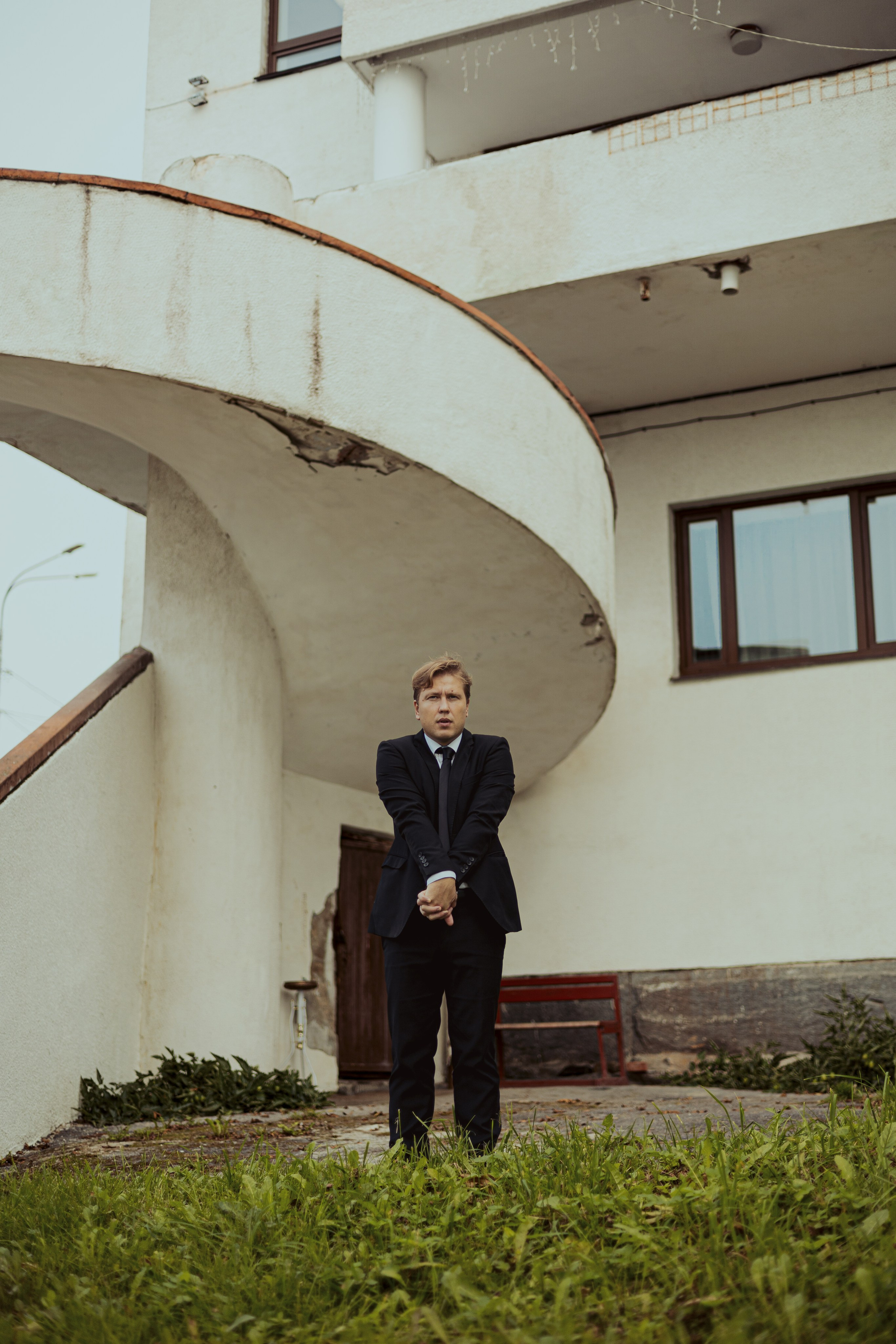 Мужчина в костюме выкручивает себе руки