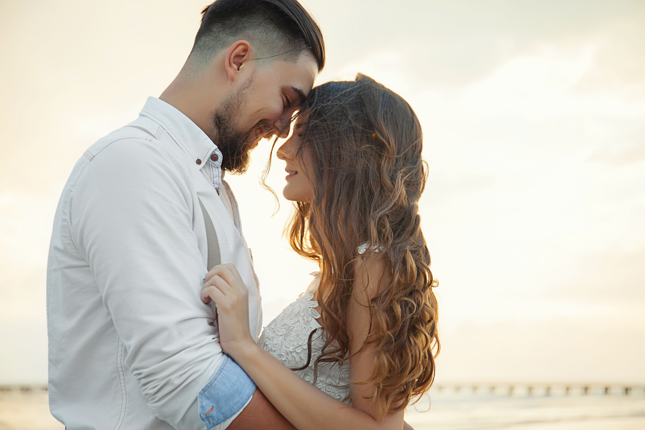 влюбленные стоят обнявшись на закате у моря