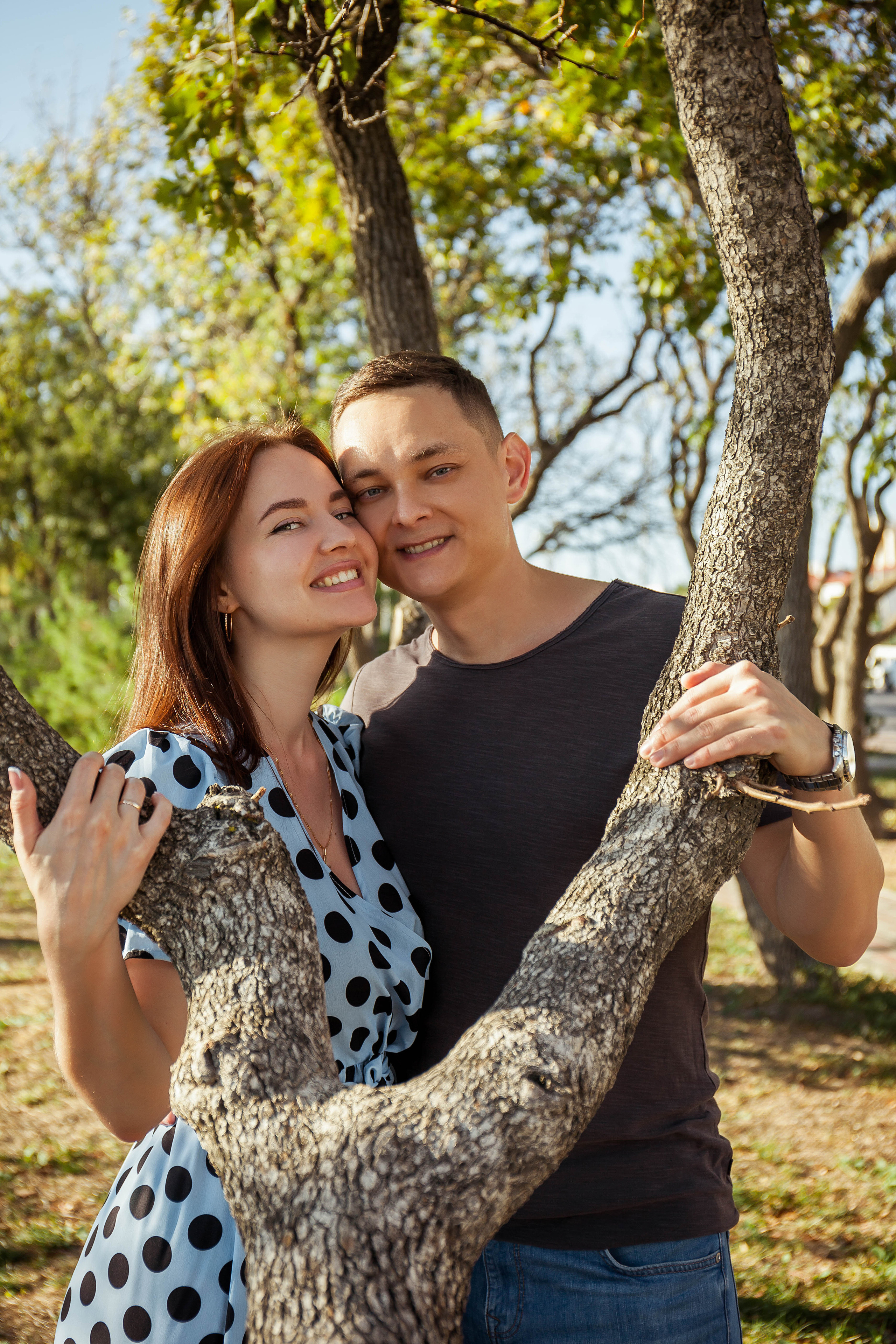 девушка и молодой человек стоят обнявшись у дерева