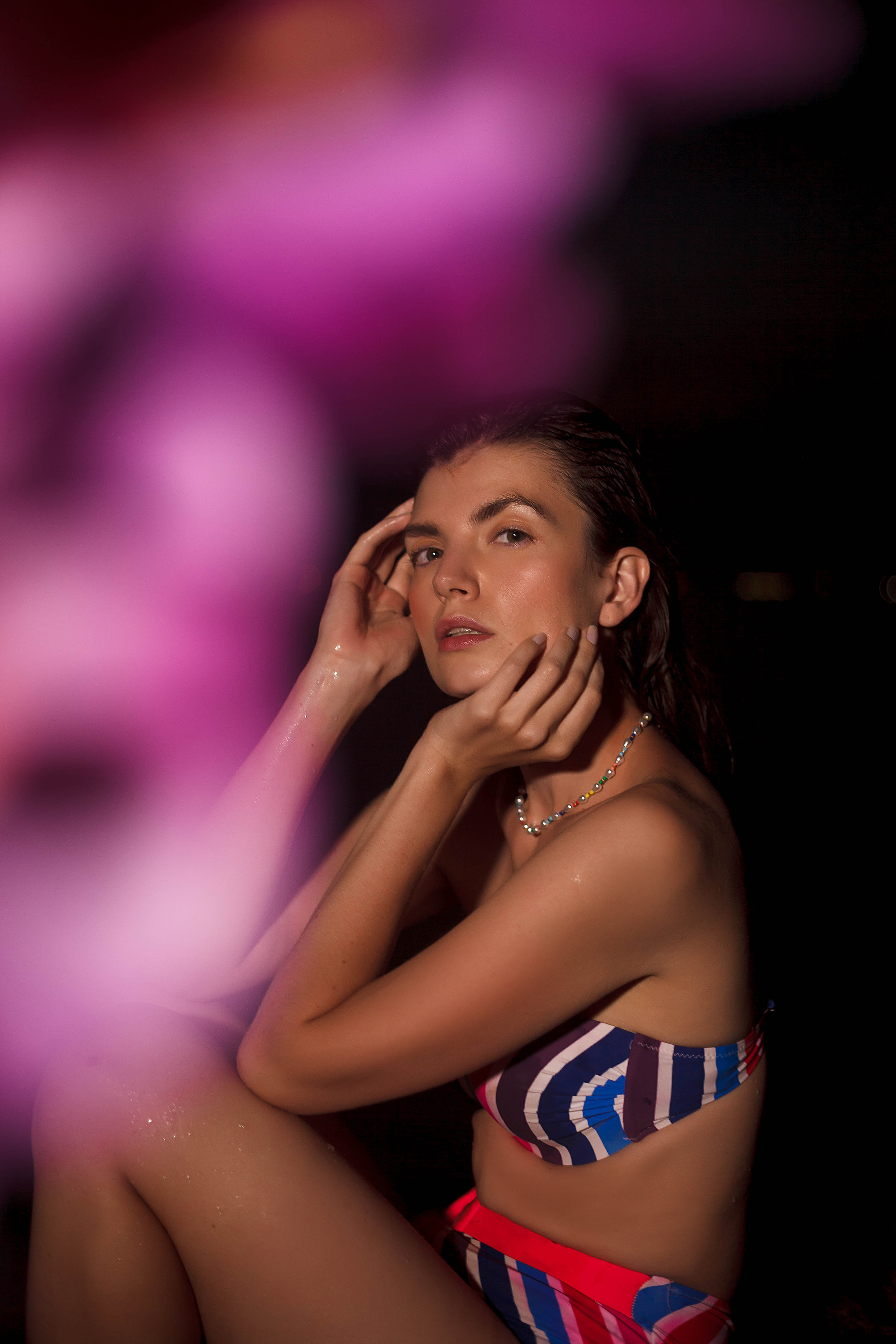 девушка в сиреневом купальнике сидит ночью на пляже геленджика