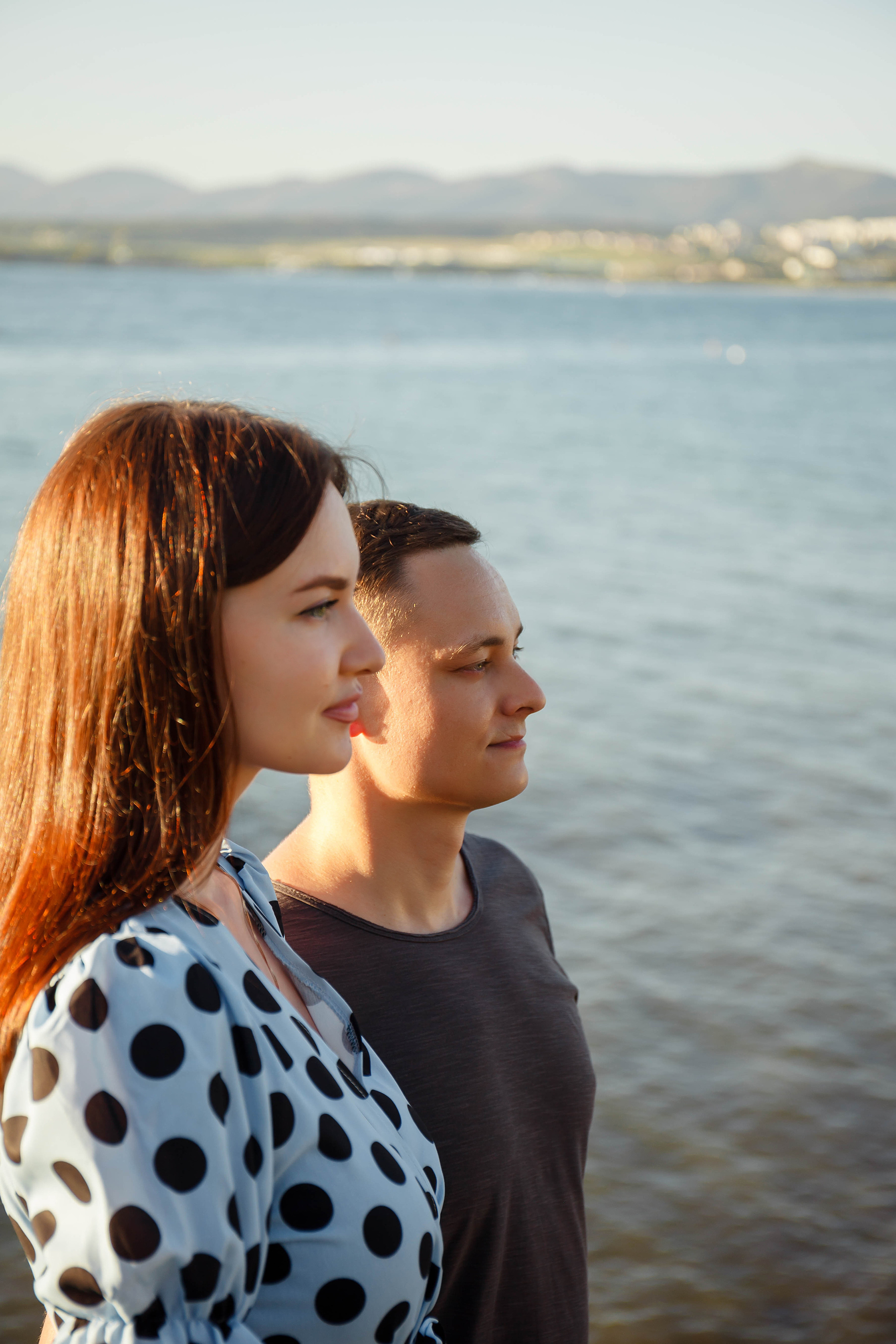 девушка в голубом платье стоит в профиль на первом плане, а на втором молодой человек