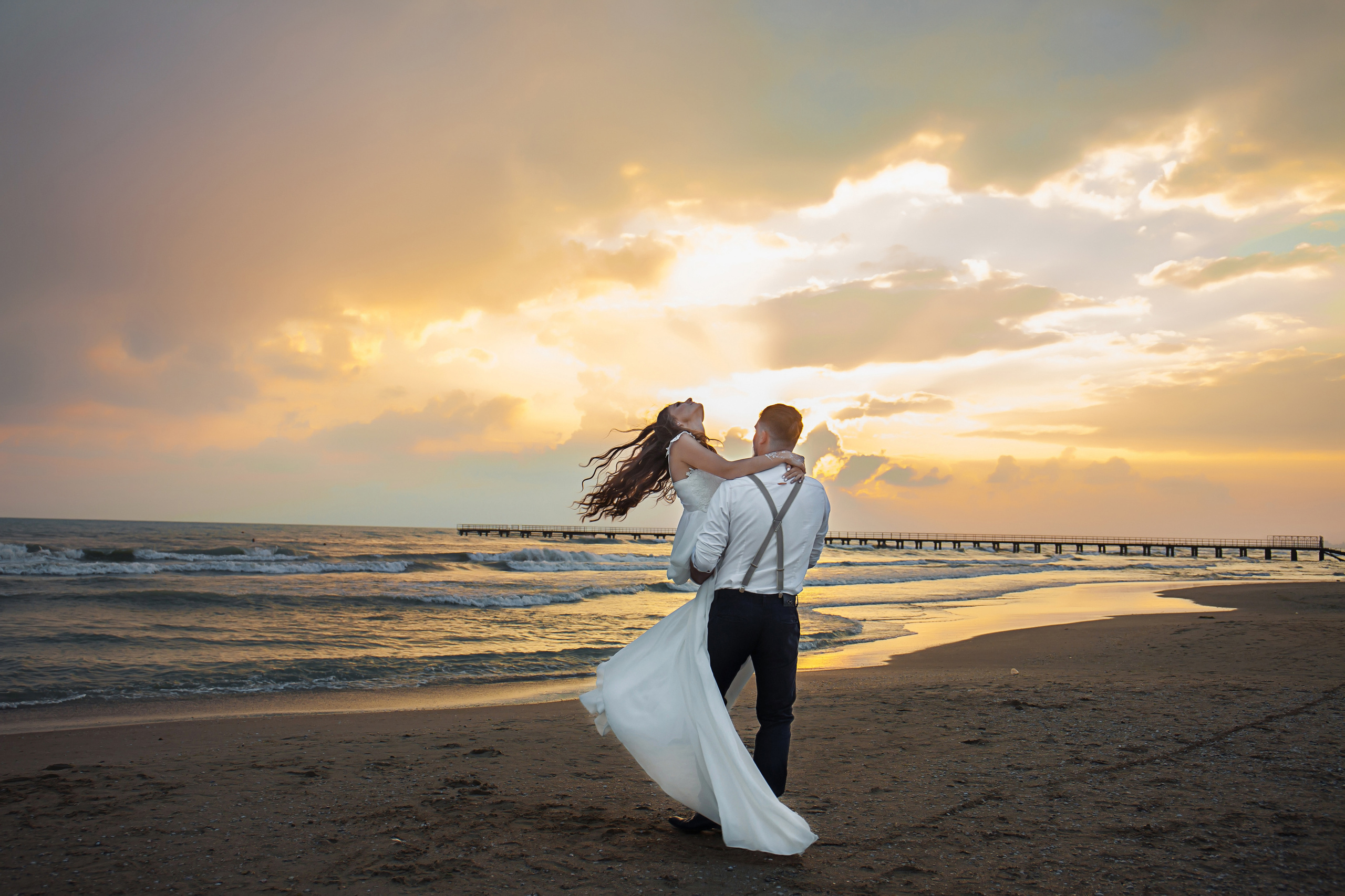 молодой человек держит девушку на руках у моря