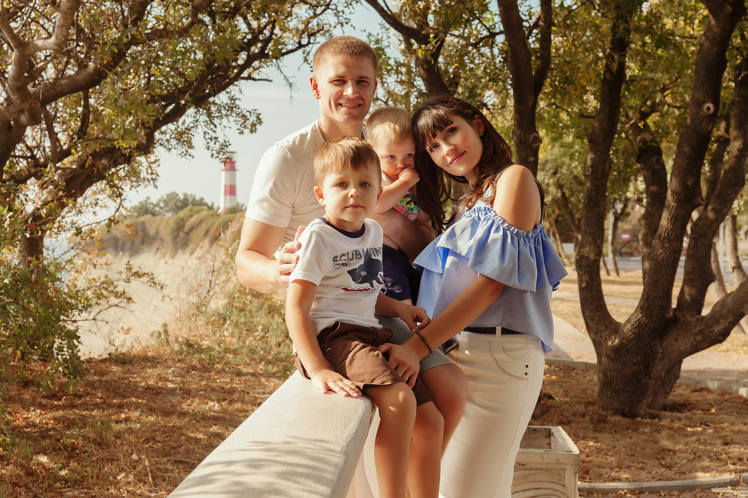 семейное фото на толстом мысе на фоне маяка муж с женой и двумя сыновьями