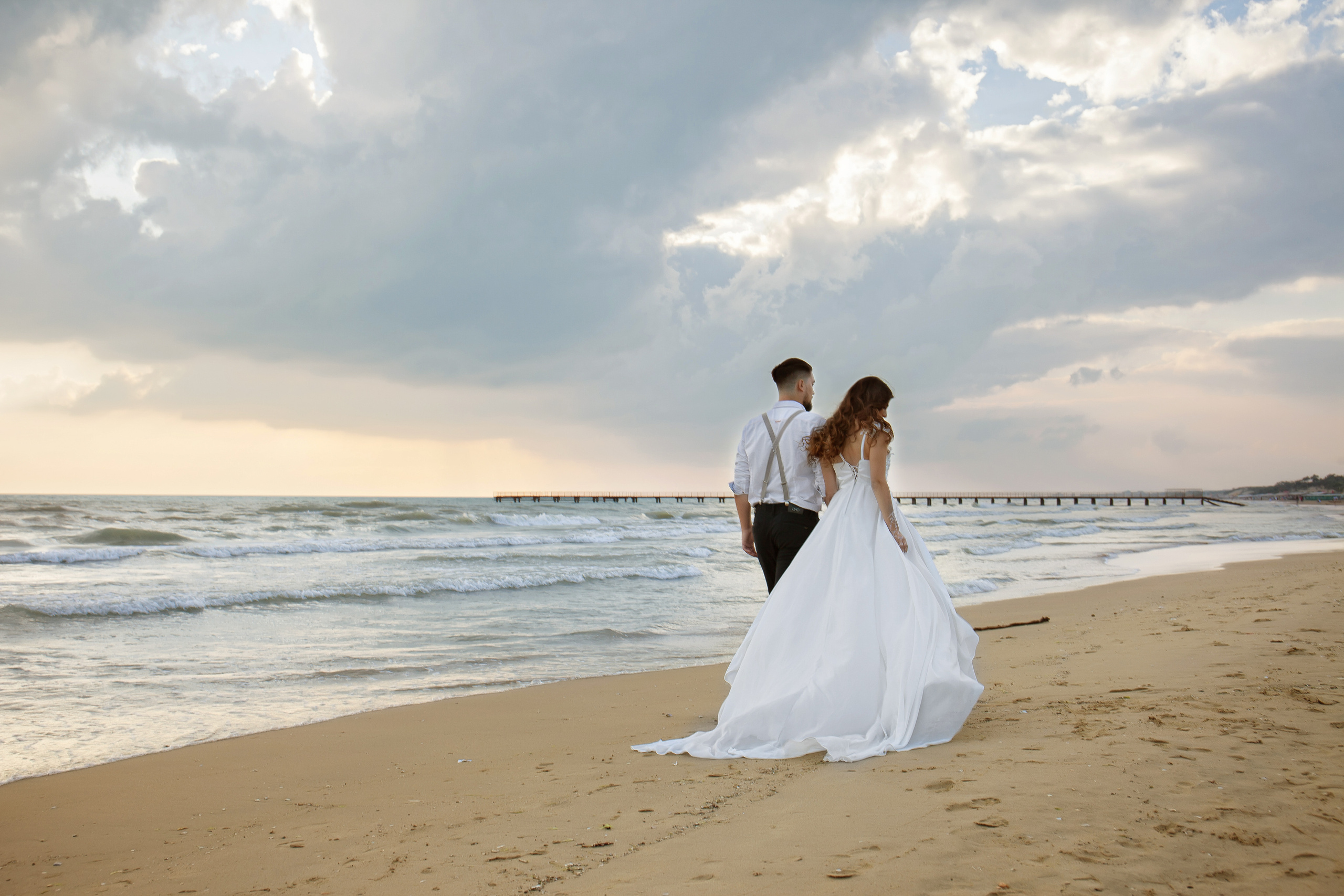 молодой человек и девушка прогуливаются вдоль моря