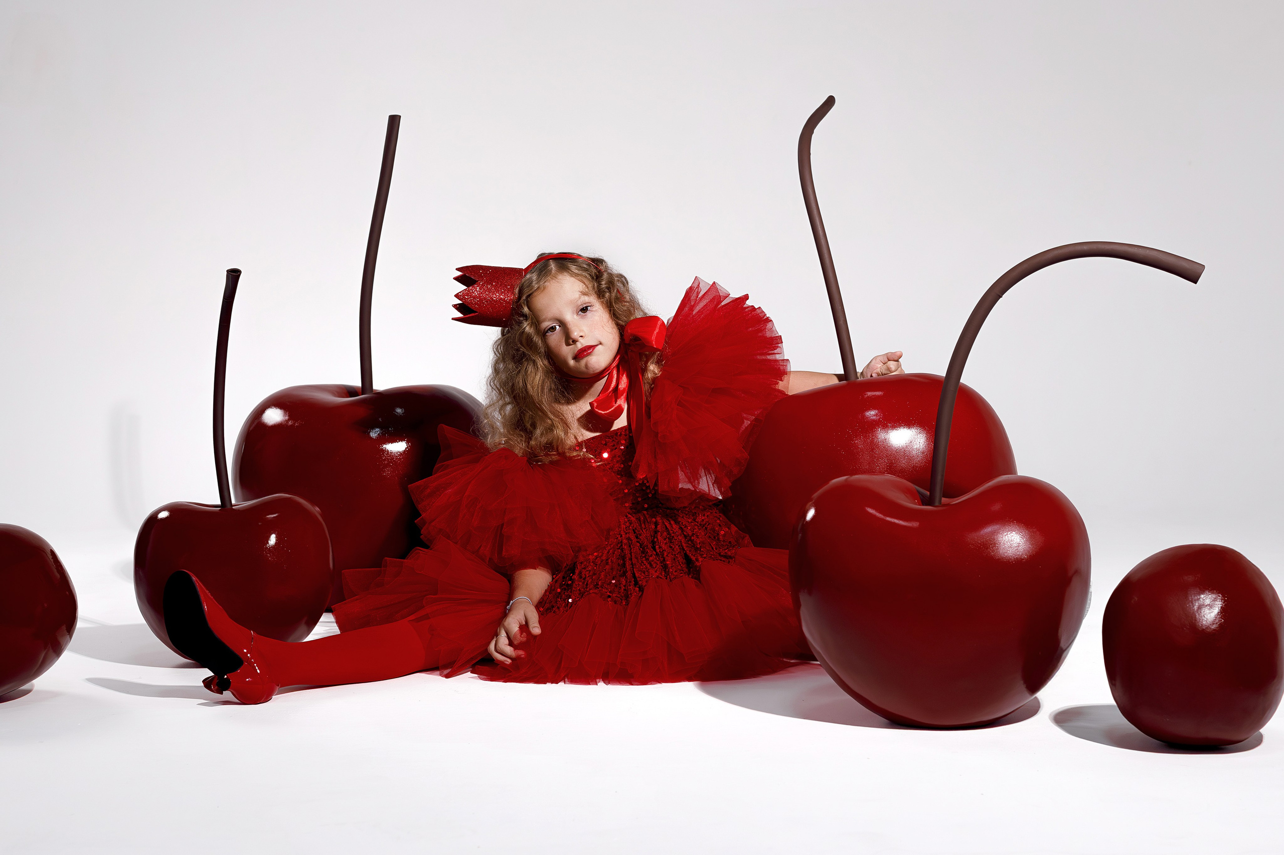 Девочка сидит на полу в окружении больших вишен