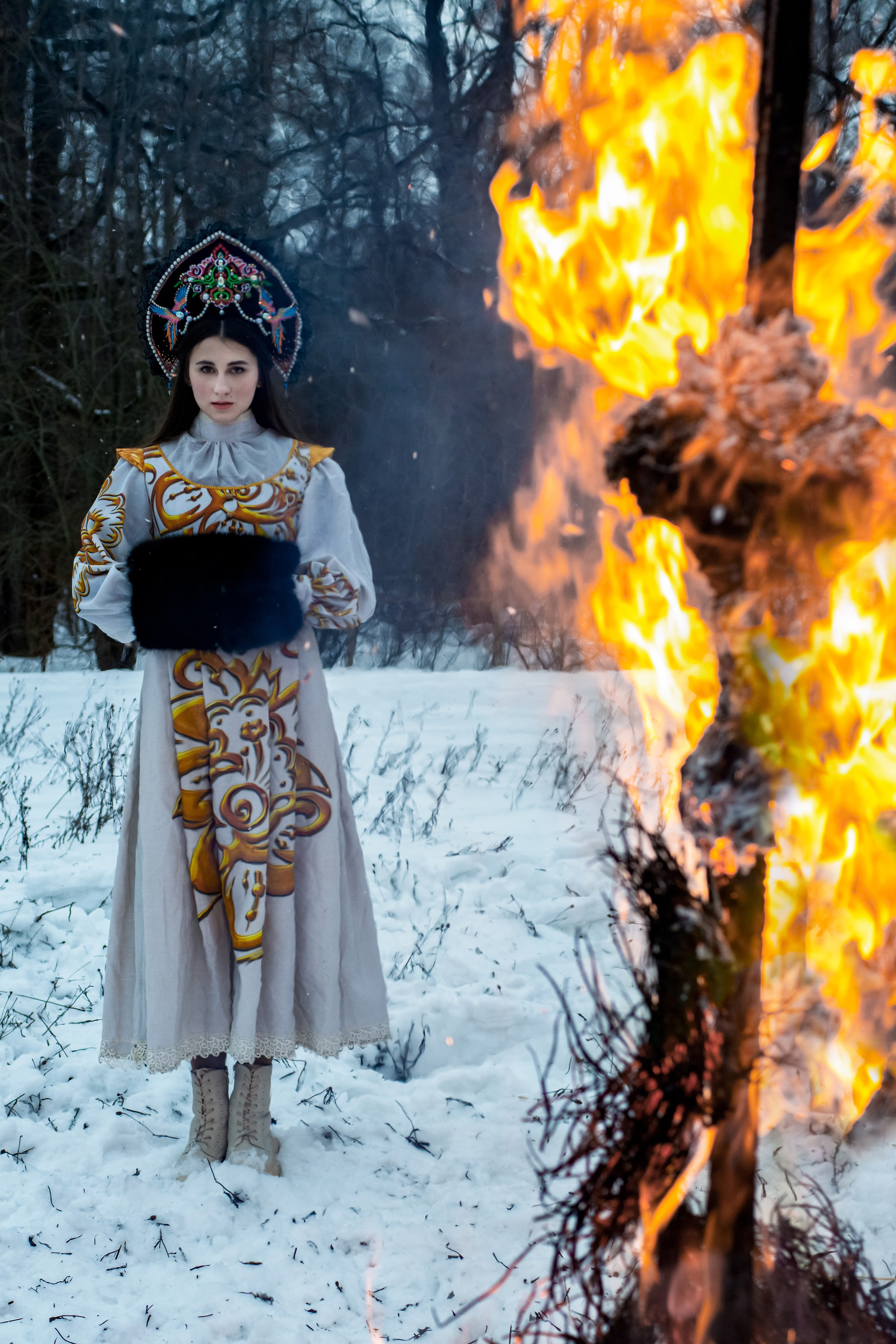 Девушка в русском-народном костюме зимой на масленицу на фоне костра 