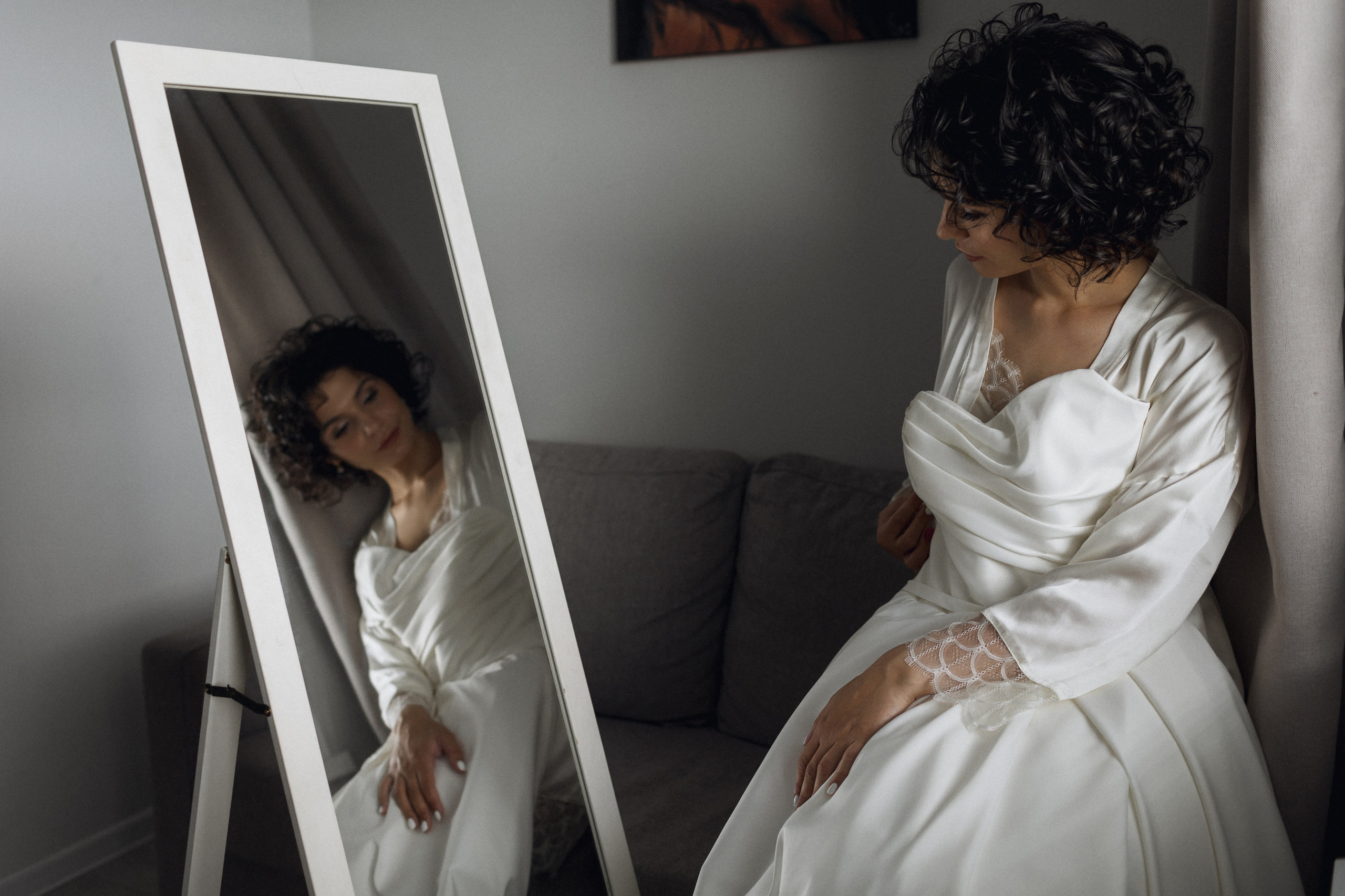 Гармония линий и эмоций: невеста в атласном платье у зеркала с геометрией отражений и мягким светом, подчеркивающим текстуру ткани