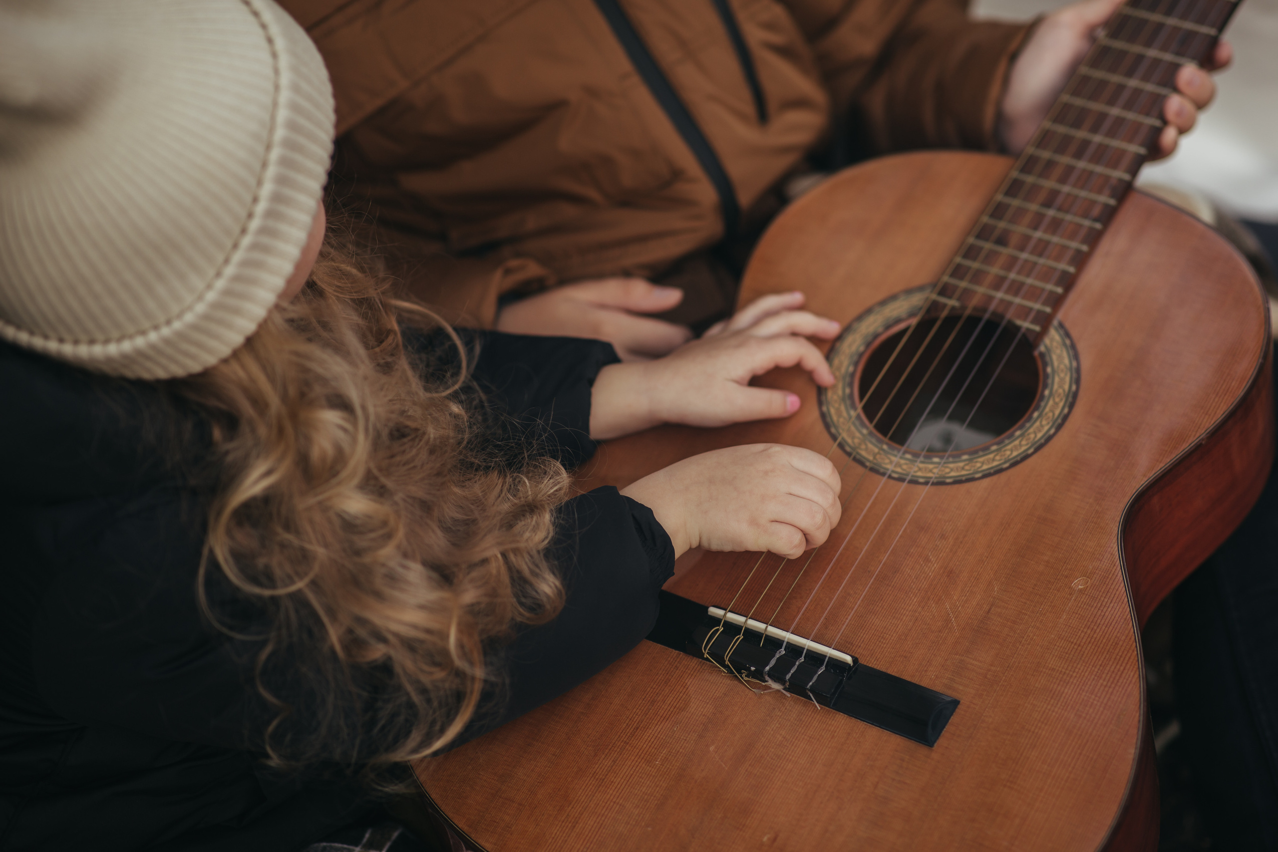 девочка в белой шапке играет на гитаре