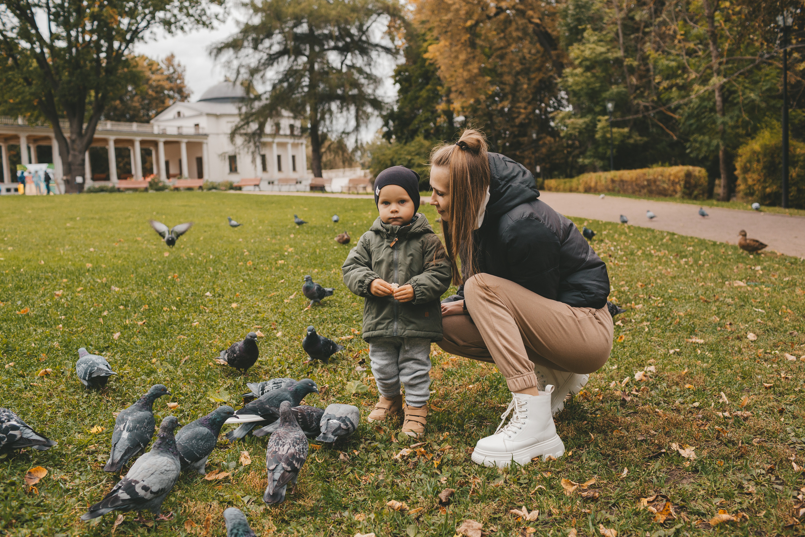 Мама с сыном кормят птиц. голуби