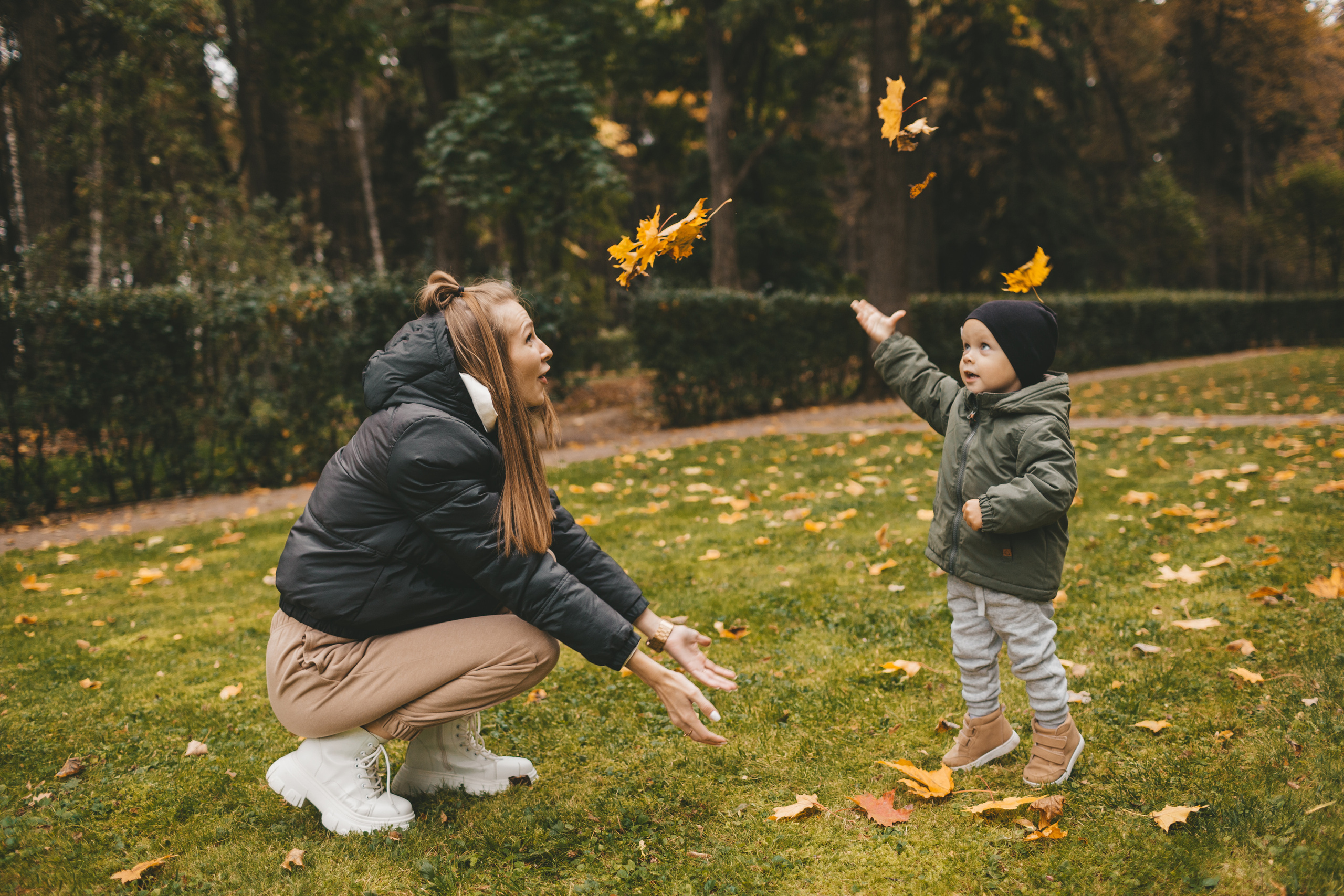 Мама с сыном обкидываются осенними листьями