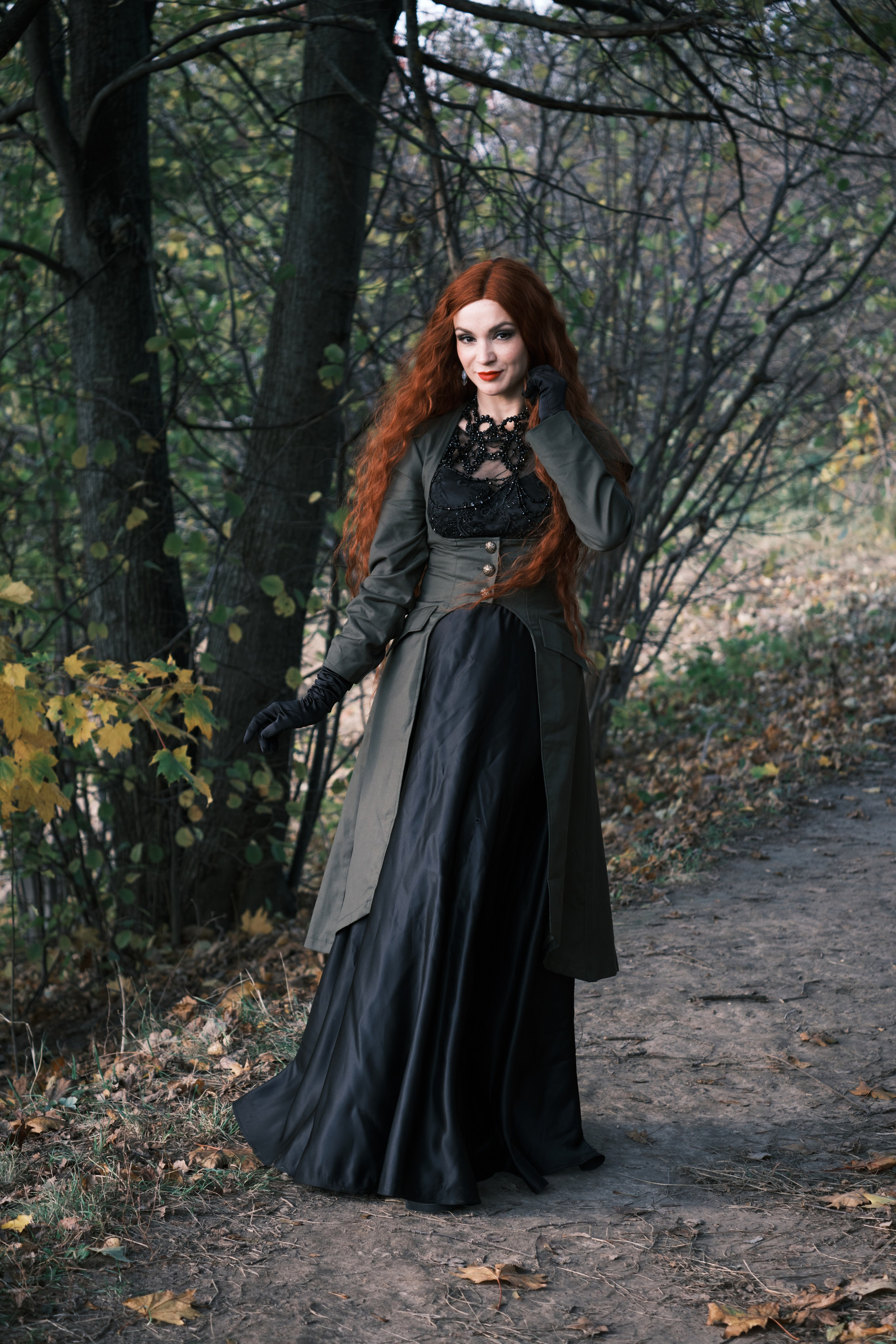 Девушка вампир стоит в лесу в старинном наряде