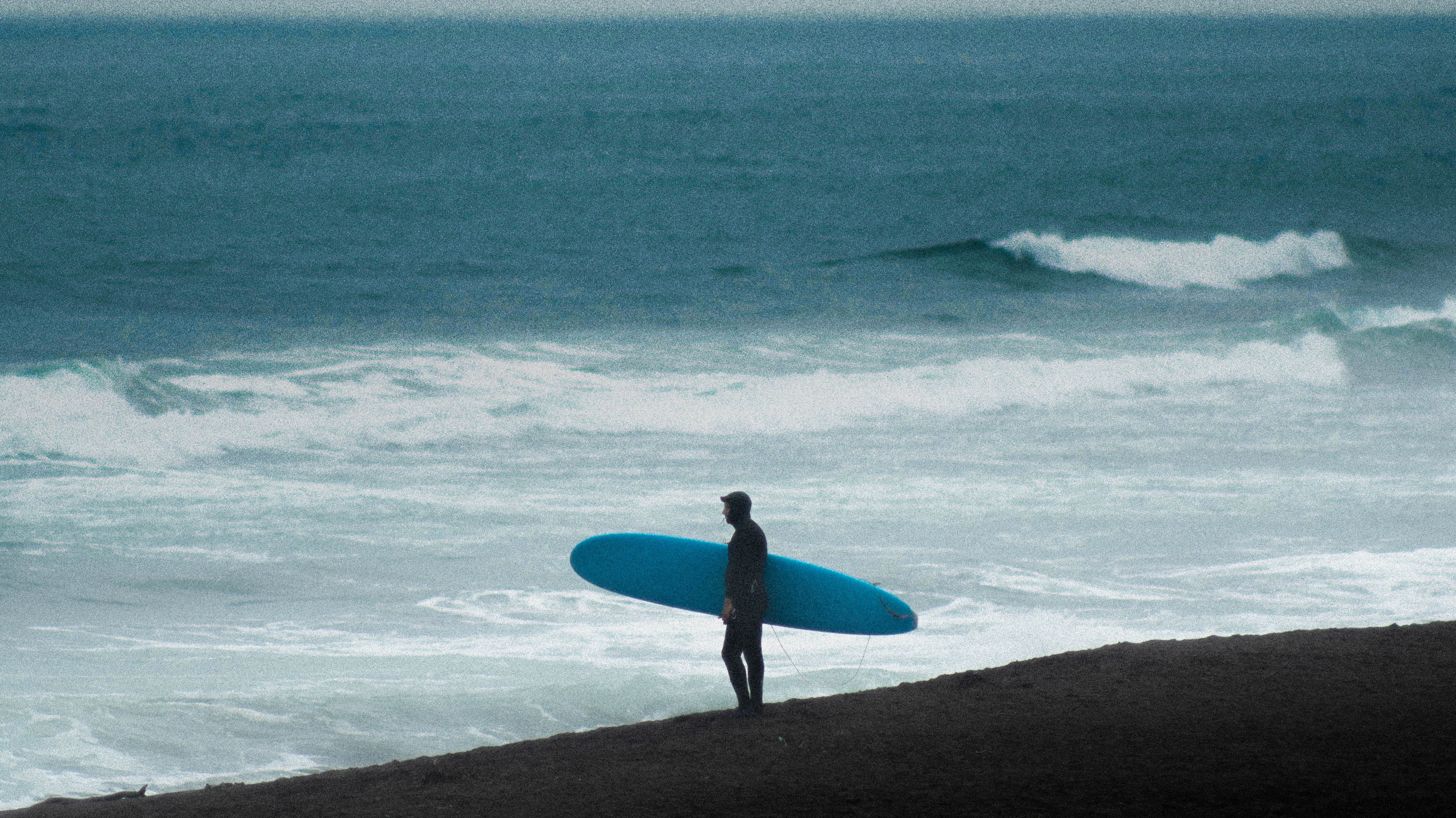 Сёрфер с доской перед выходом в океан на Халактырском пляже Камчатки