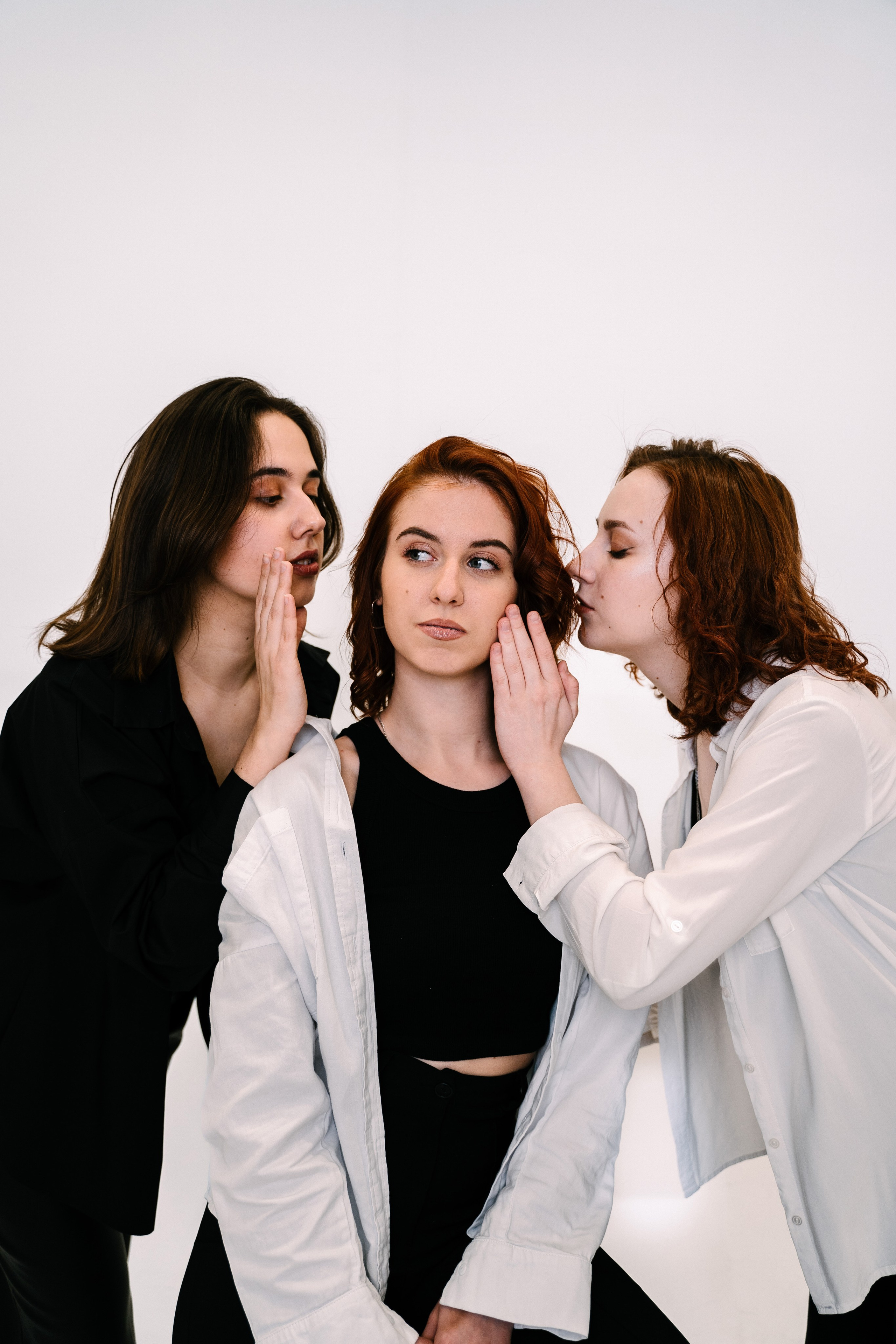 две девушки шепчут третьей девушке на ухо 