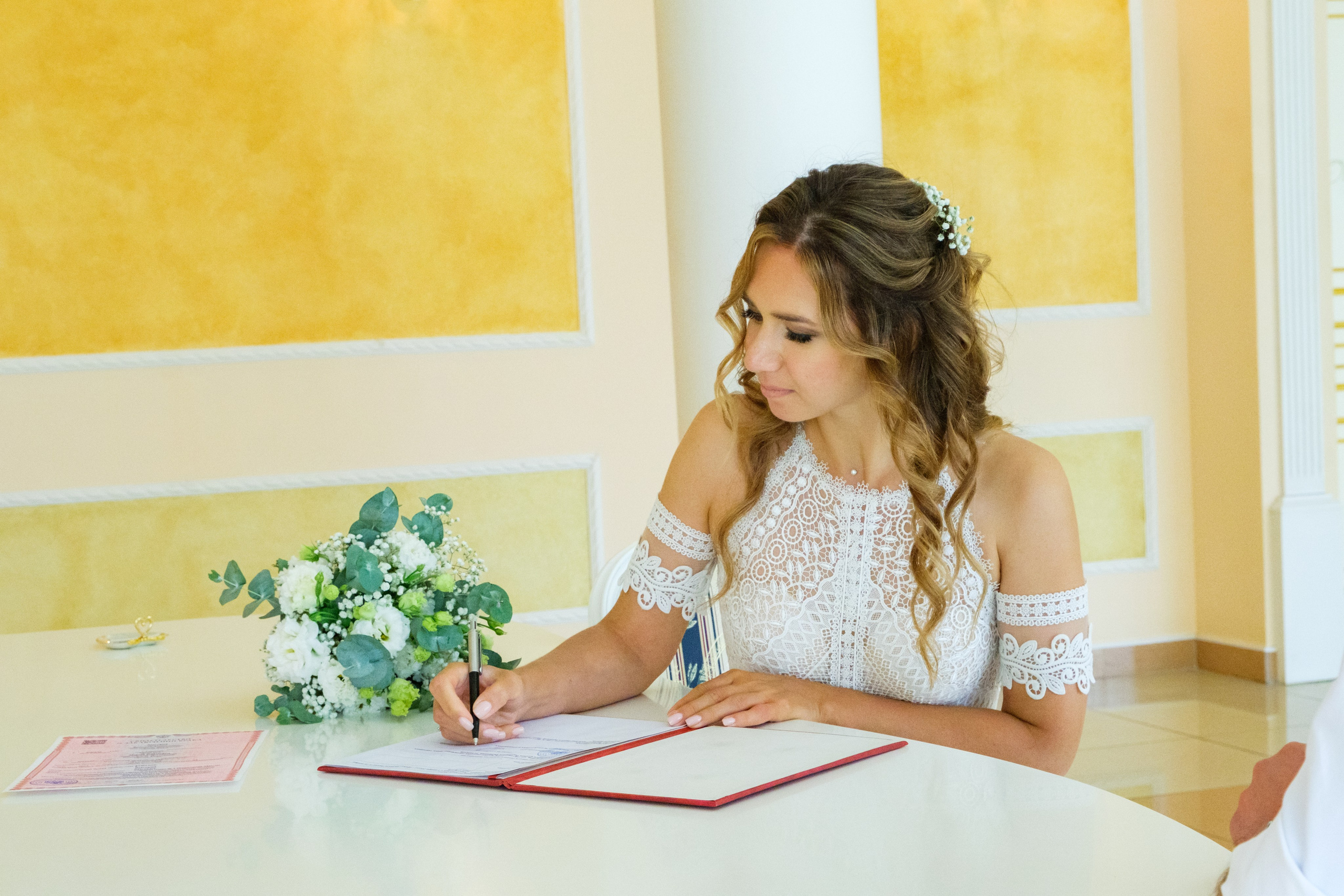 Подпись в свидетельстве о браке: молодожены подписывают документы, их руки вместе, символизируя начало новой жизни.