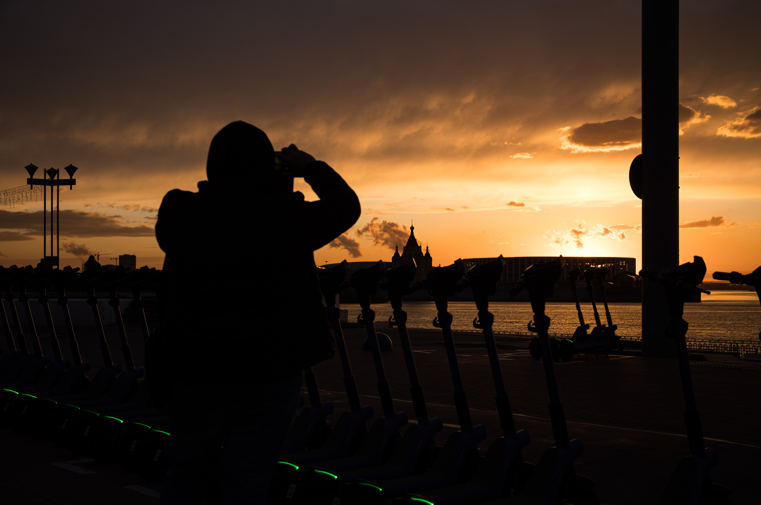 Вид на Стрелку в Нижнем Новгороде на закате в золотистых цветах с контрастным силуэтом на переднем плане