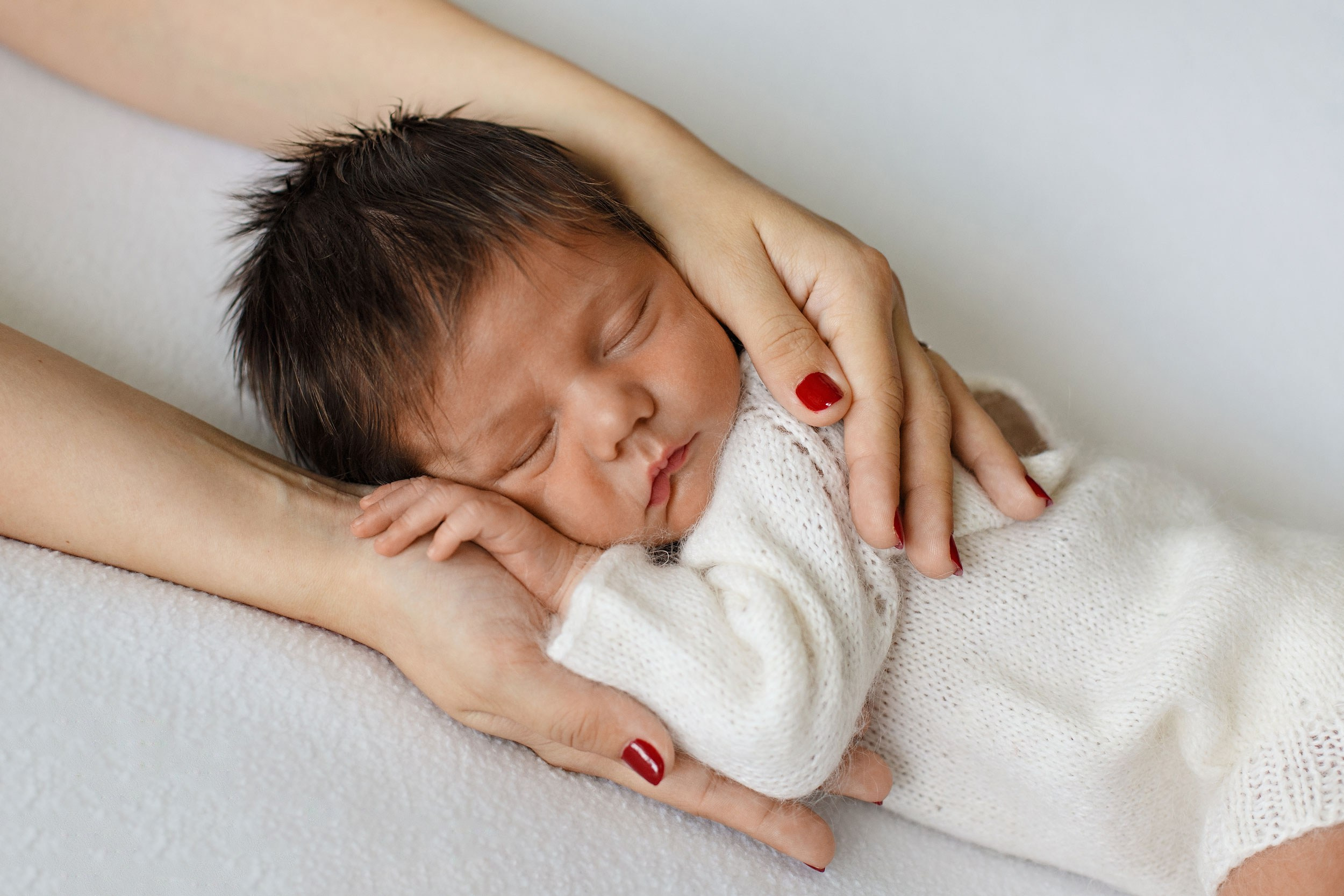 Новорожденный сладко спит  в маминых руках