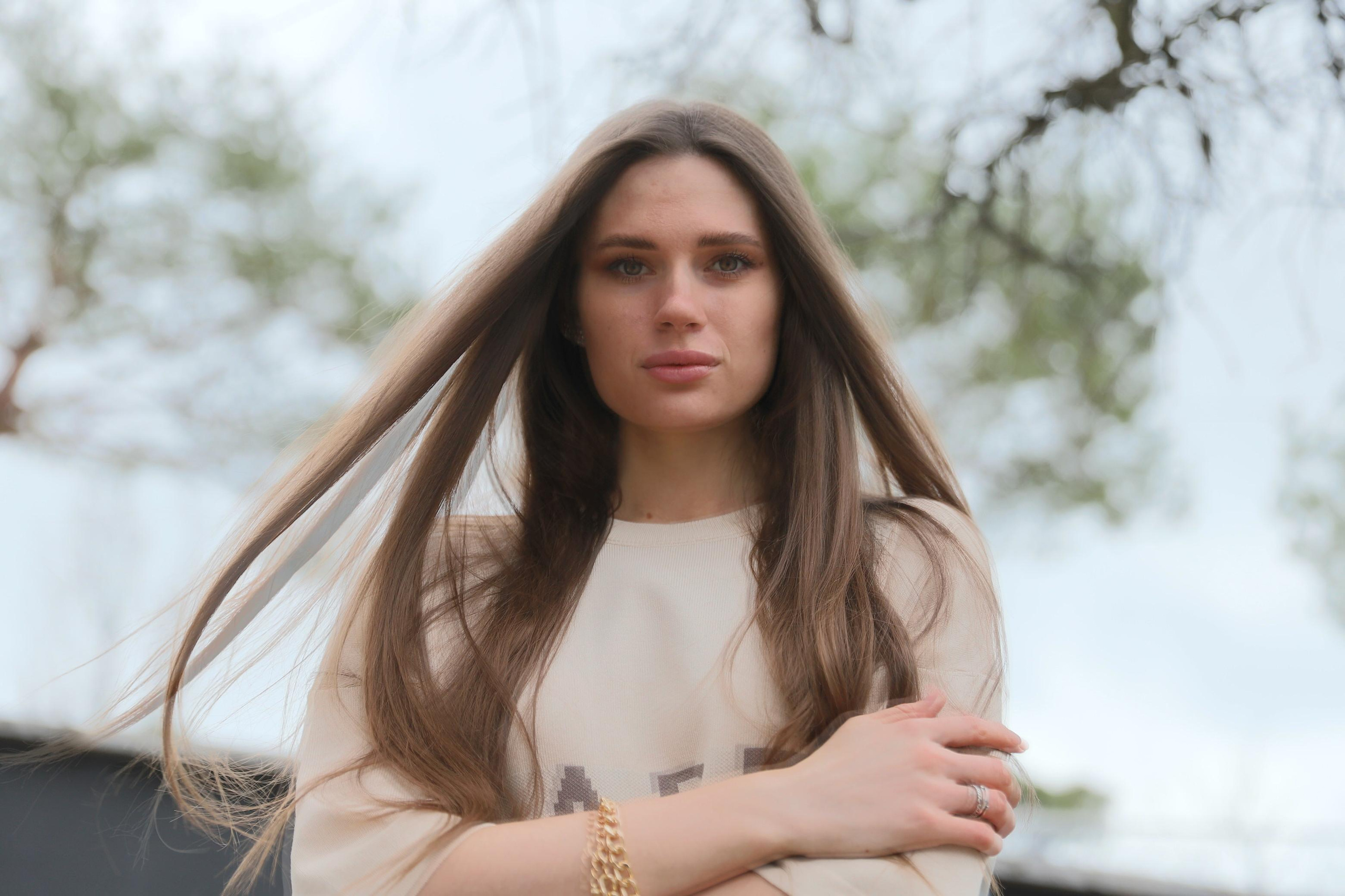 Девушка с длинными волосами на природе на фоне деревьев и серого неба
