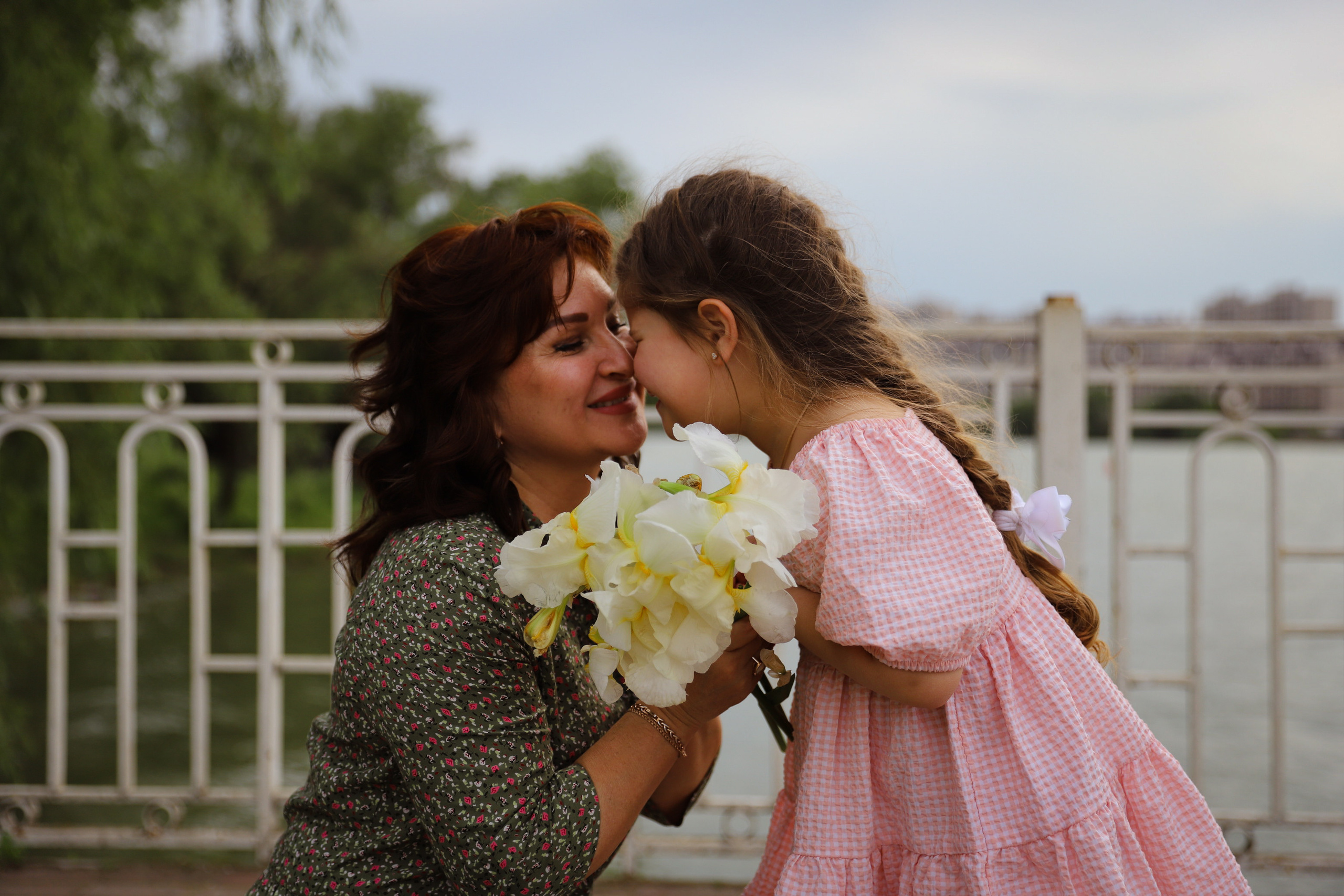 Счастливая бабушка и внучка смеются друг с другом во время прогулки по солнечной набережной реки Кубань