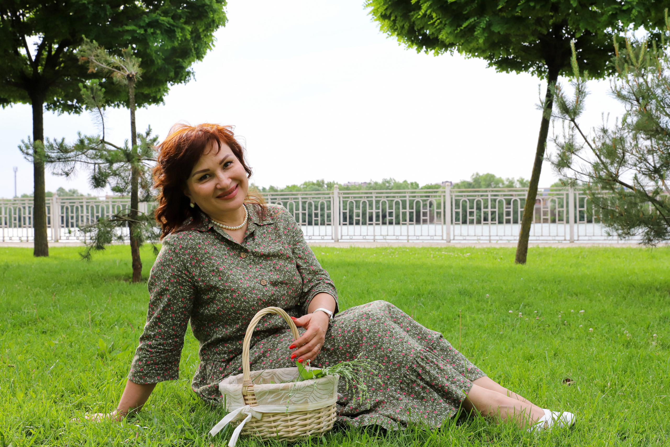 Улыбчивая женщина с корзинкой на фоне зелени на набережной 