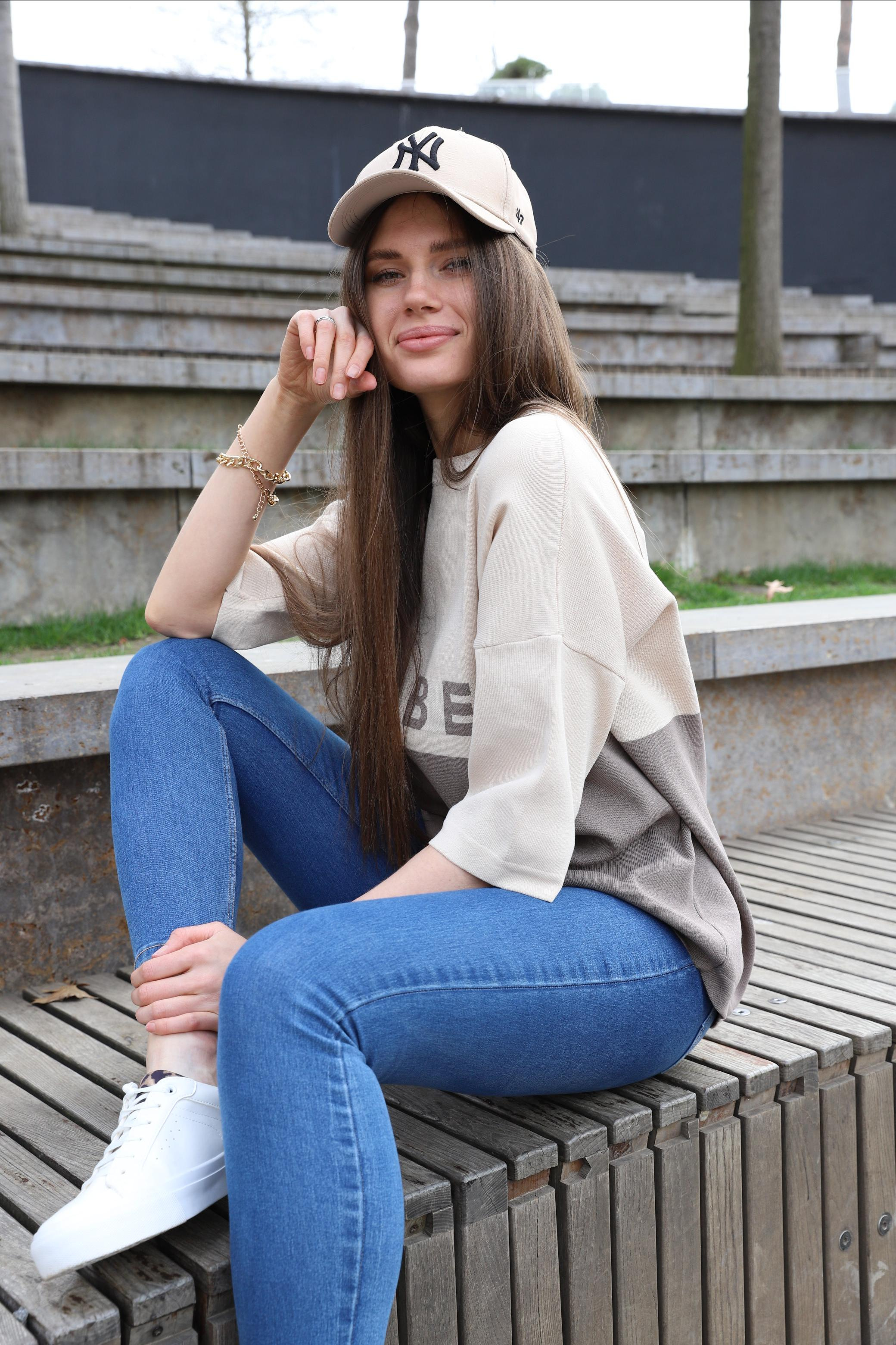 Спортивная девушки в бейсболке  сидит в амфитеатре парка Краснодар