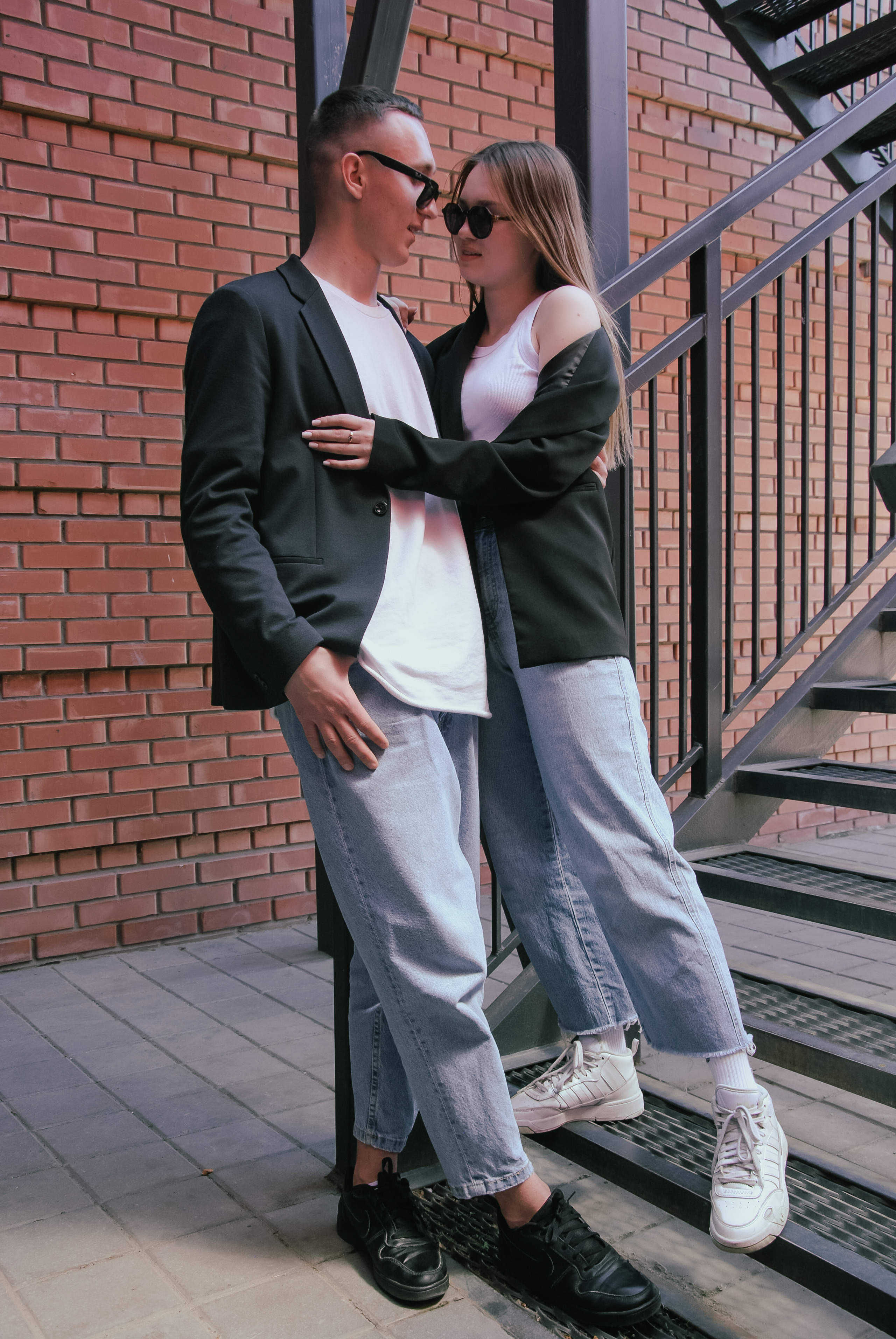 Молодой человек и его девушка обнявшись стоят на лестнице 