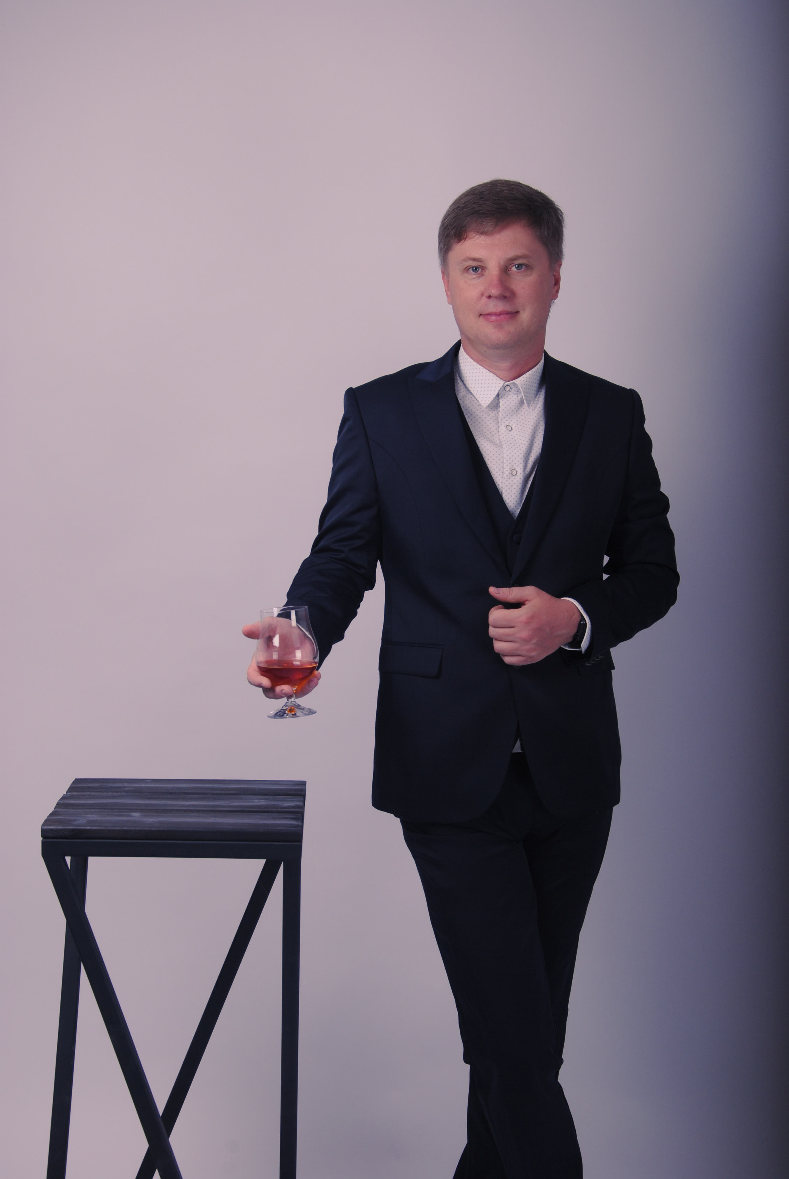Мужчина в темном костюме с бокалом виски