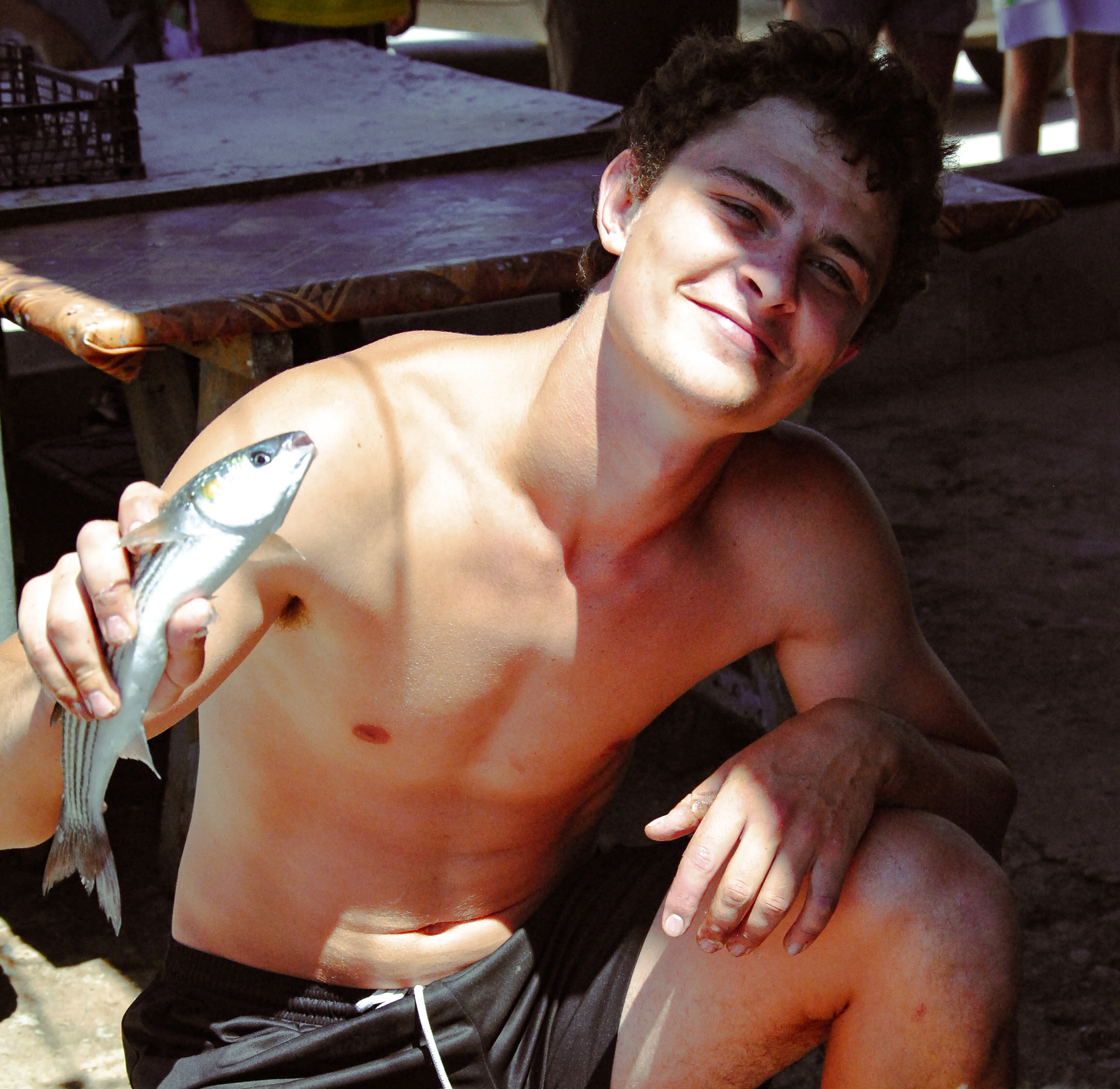 Довольный рыбак позирует со свежим уловом кефали