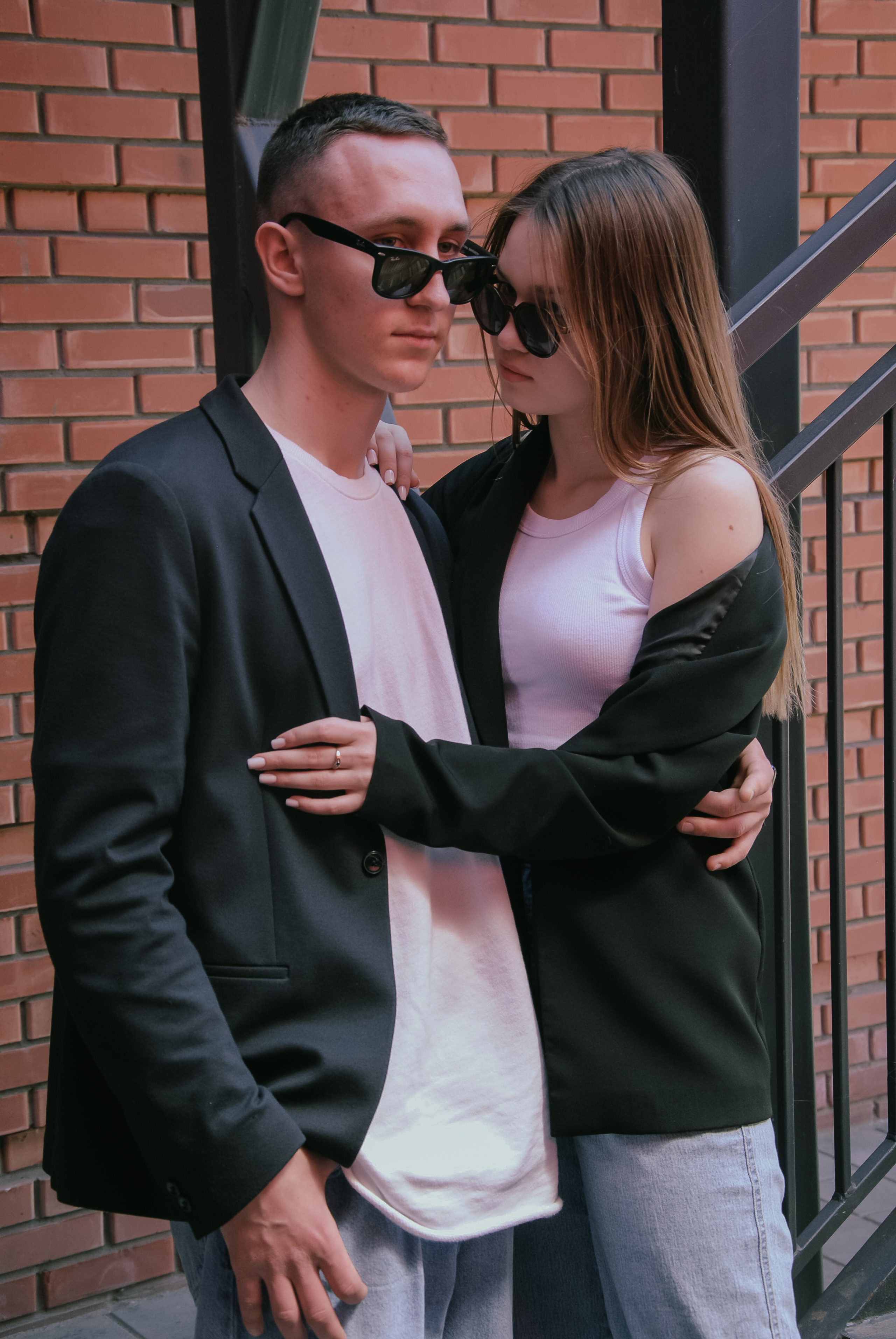 Уединение влюблённых , которые одинаково одеты в белых майках, голубых джинсах, черных пиджаках и в солнечных очках 