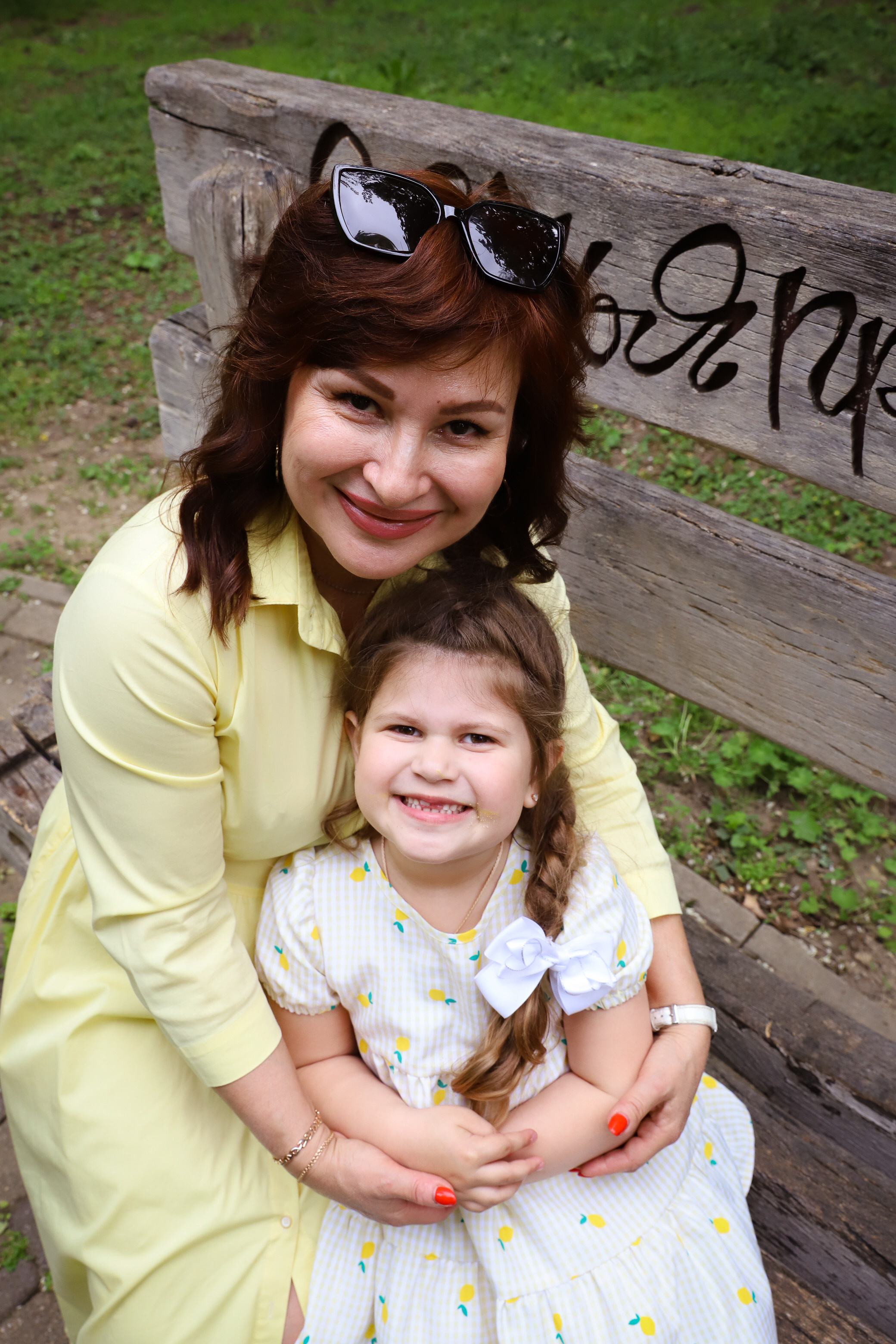 Веселая бабушка обнимает свою пятилетнюю внучку на фоне живописной набережной реки Кубань в Краснодаре.