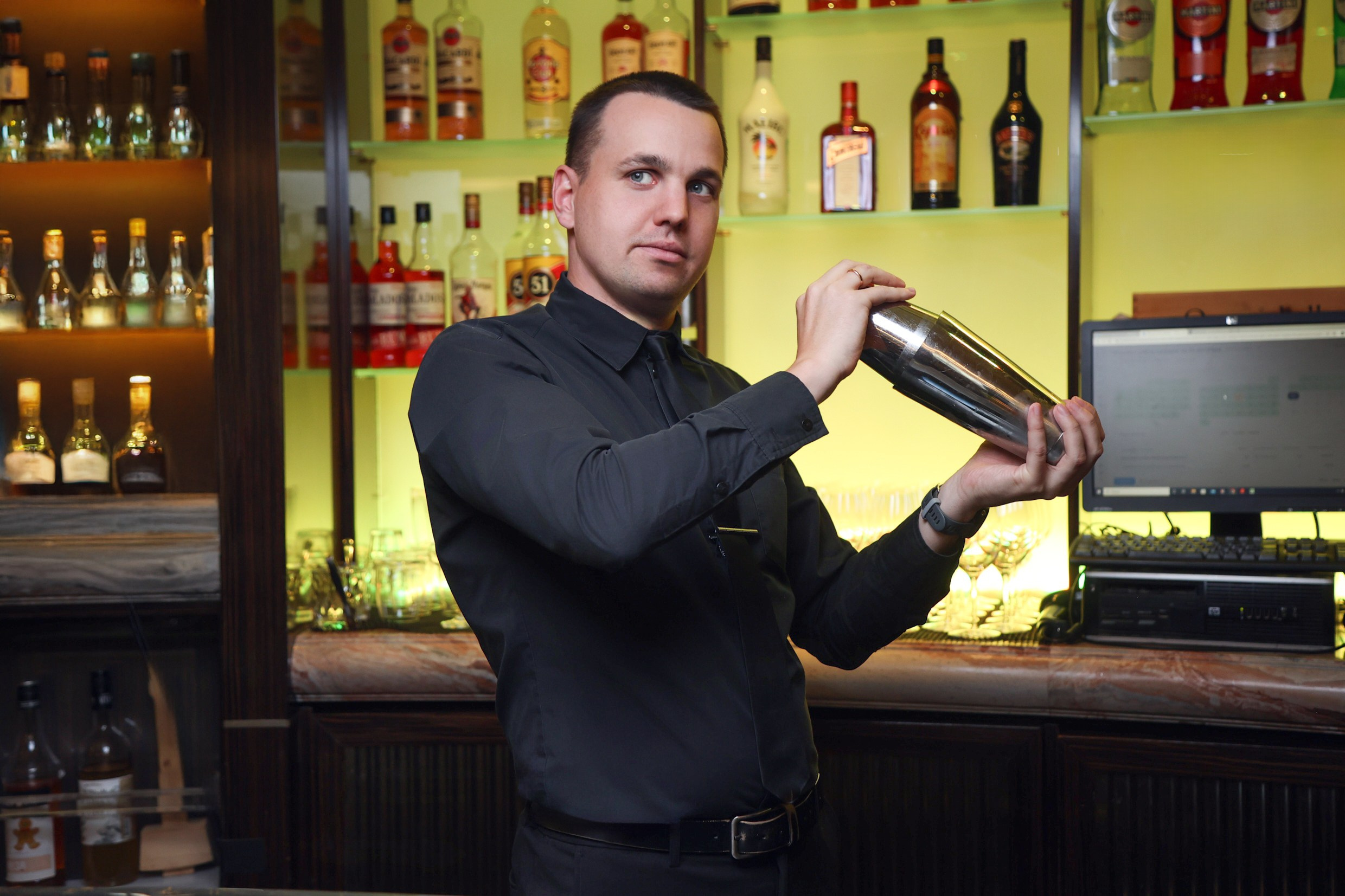 Бармен лобби-бара виртуозно работает шейкером, готовя коктейль для гостей отеля. Динамичный кадр.