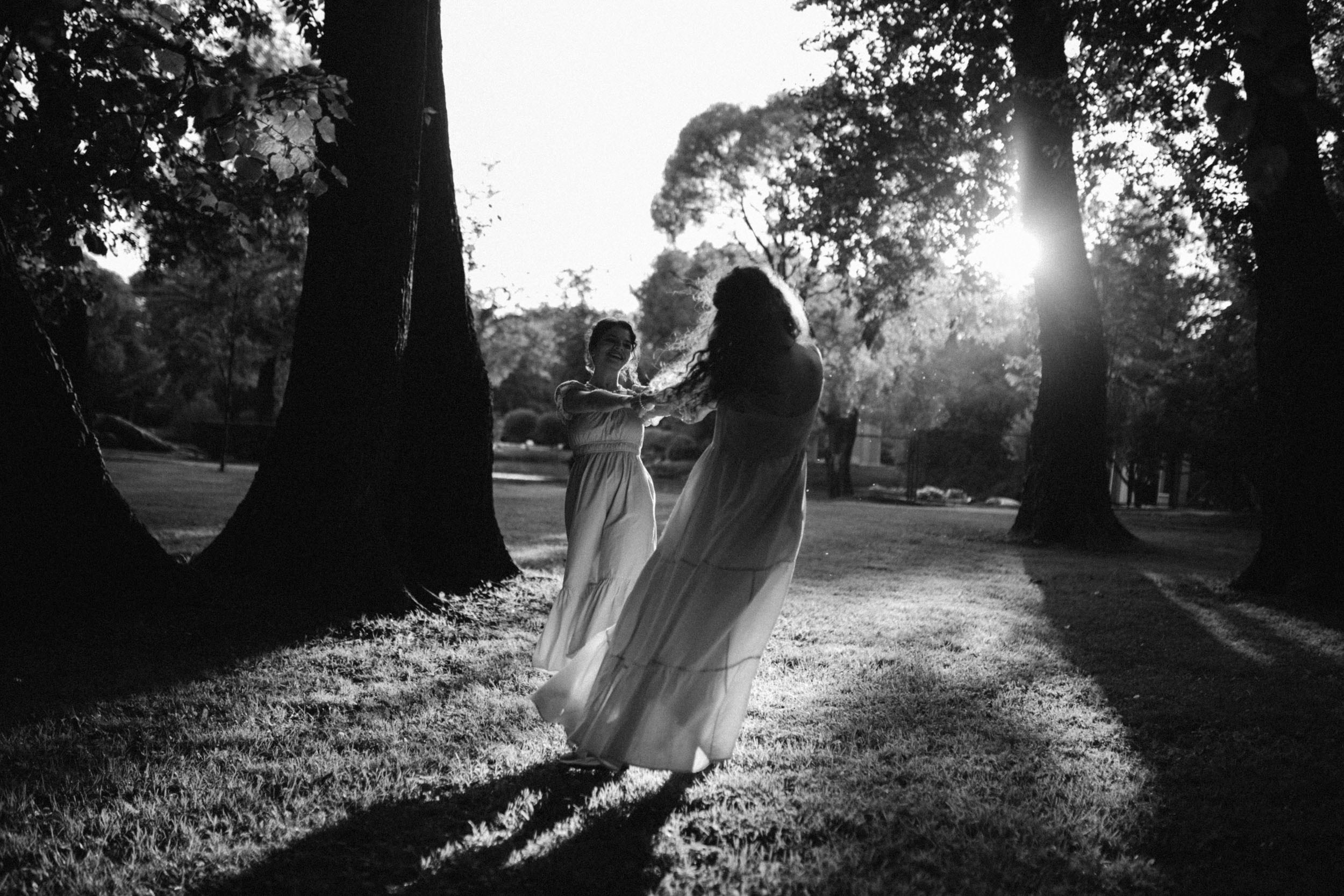 Подружки кружатся за руки на закате в платьях