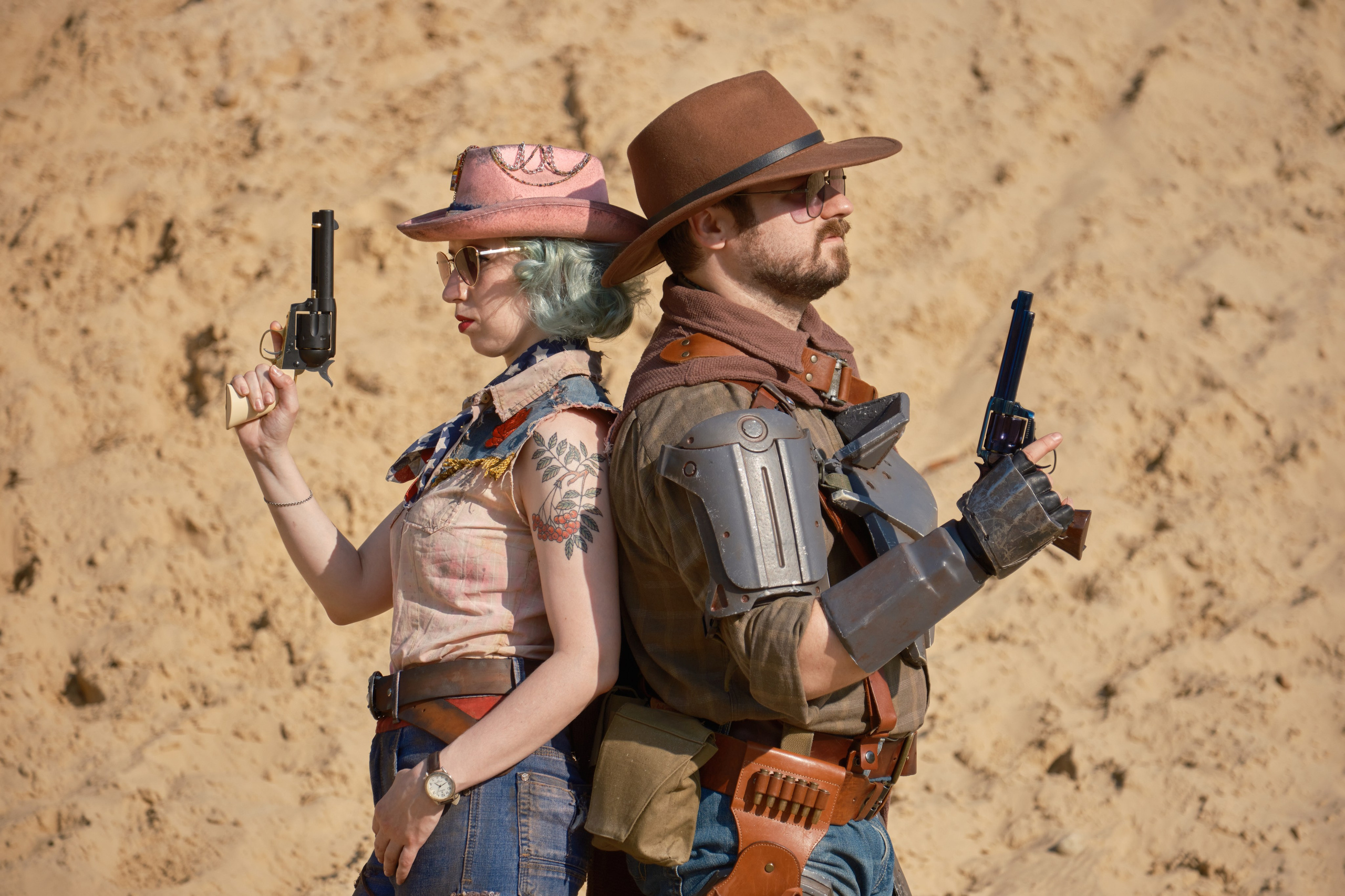 Мужчина и девушка в ковбойских шляпах и револьверами стоят спина к спине