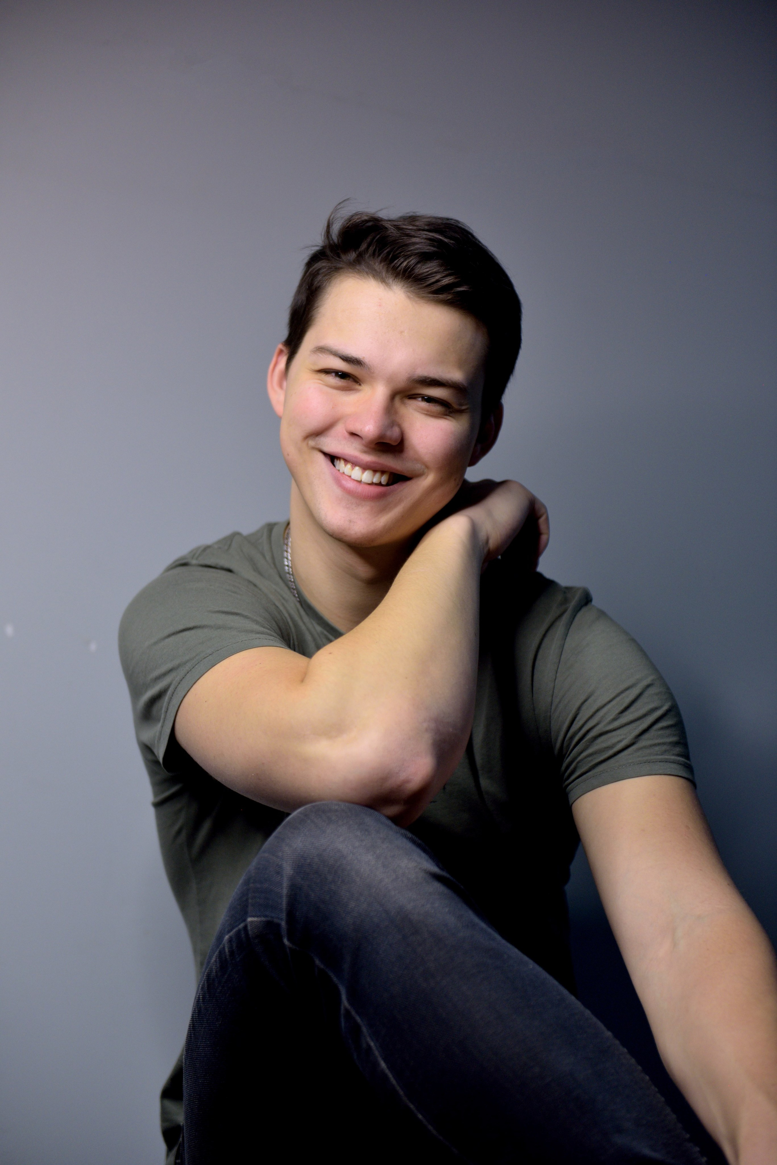 Портрет счастливого молодого человека на сером фоне.